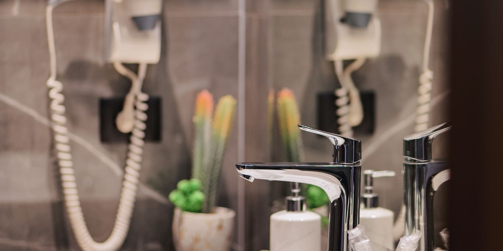Modern bathroom vanity with white sink, chrome faucet, hairdryer, and plants.