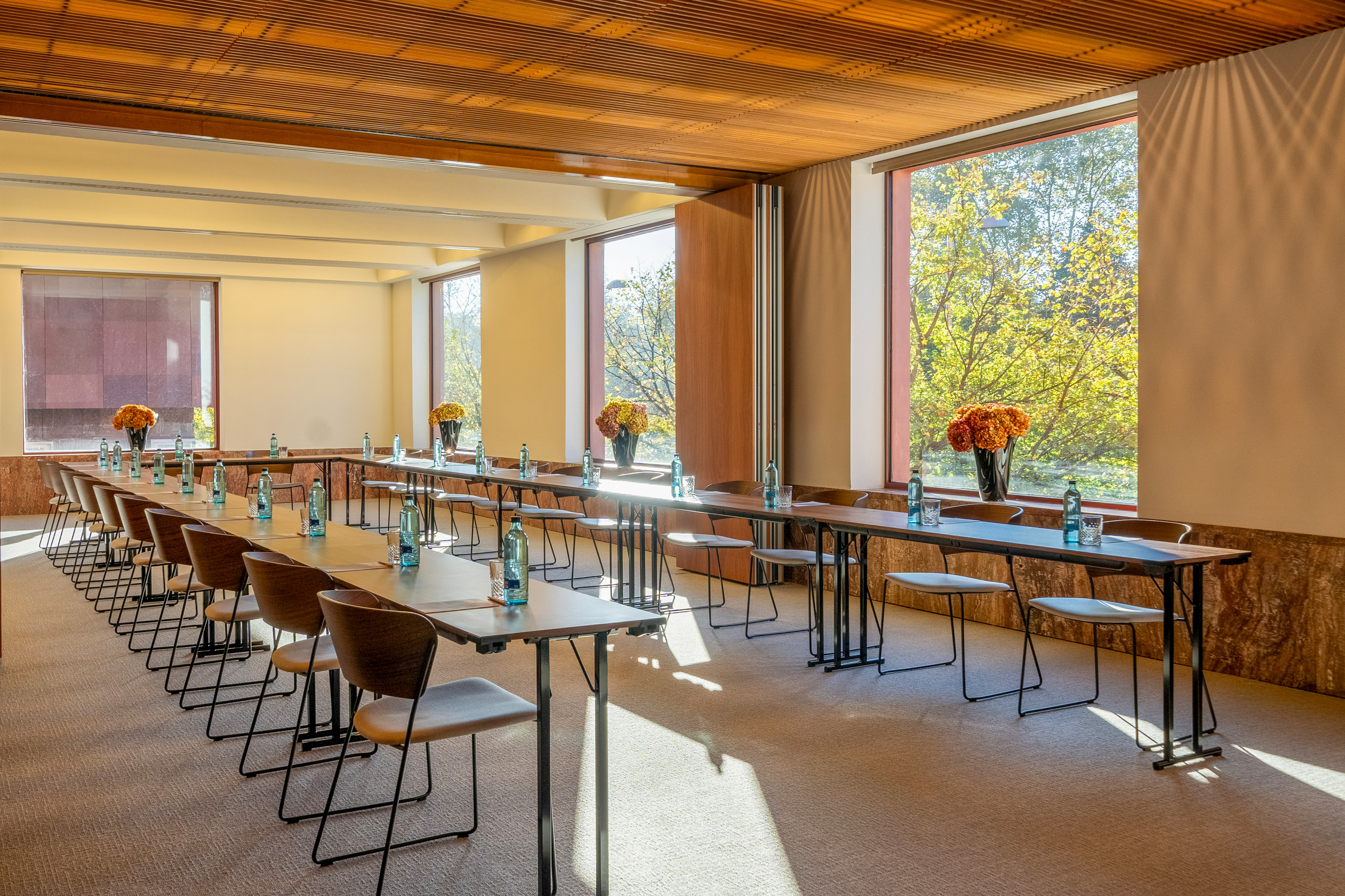 Bright conference room with U-shaped tables, natural light, and green views.