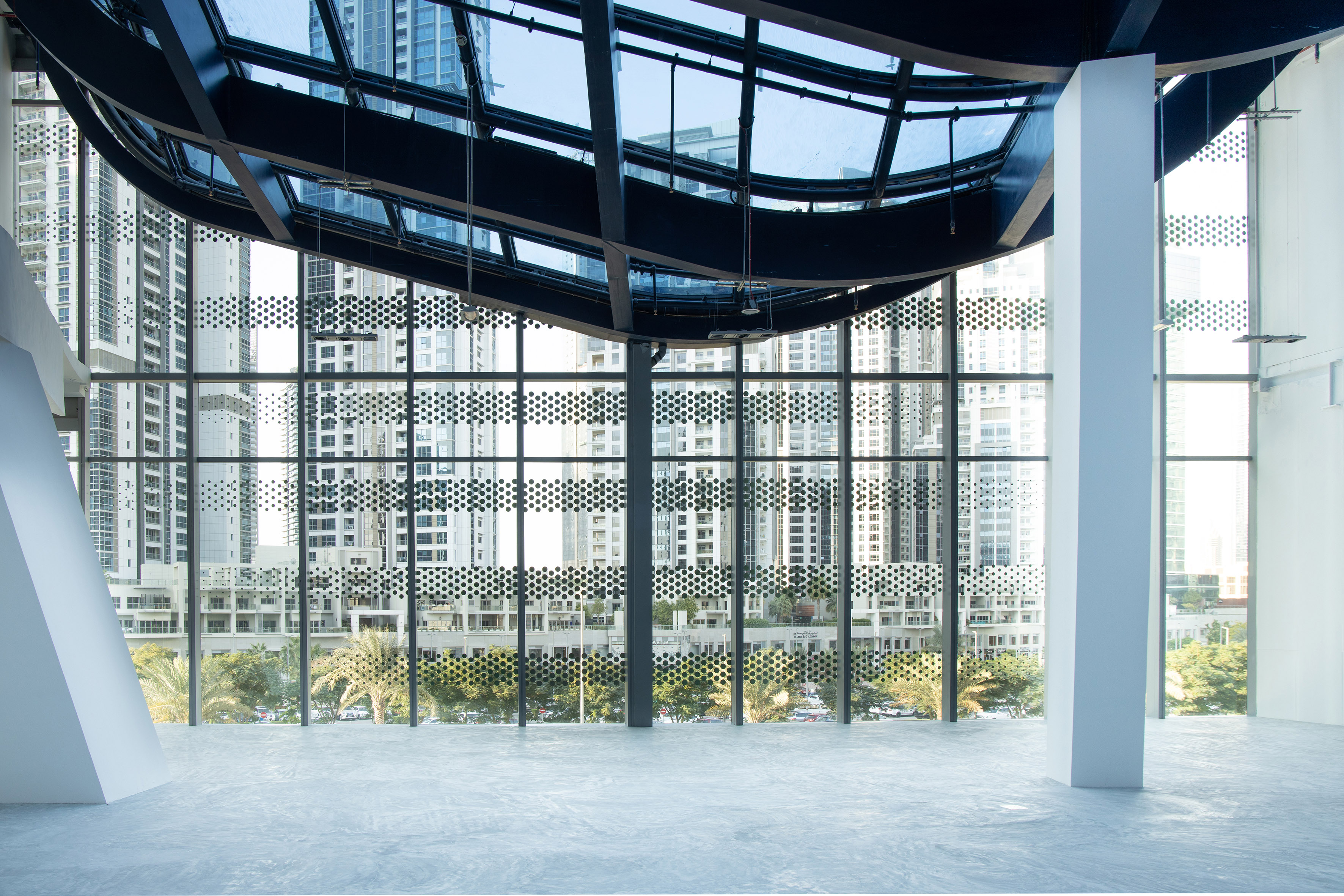 Modern interior architecture with city skyline view through patterned glass facade.