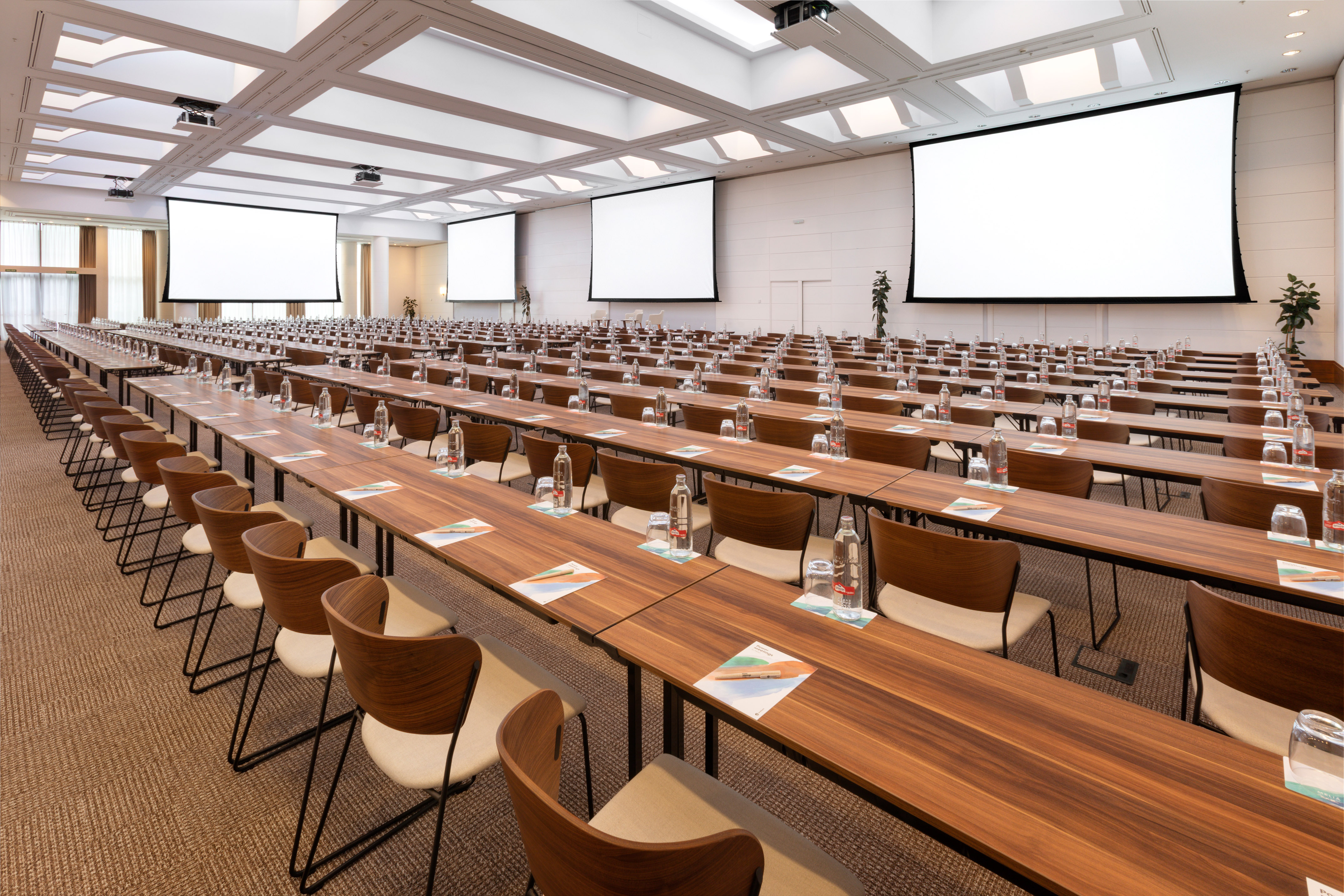 Modern conference room with tables, chairs, and large projection screens.