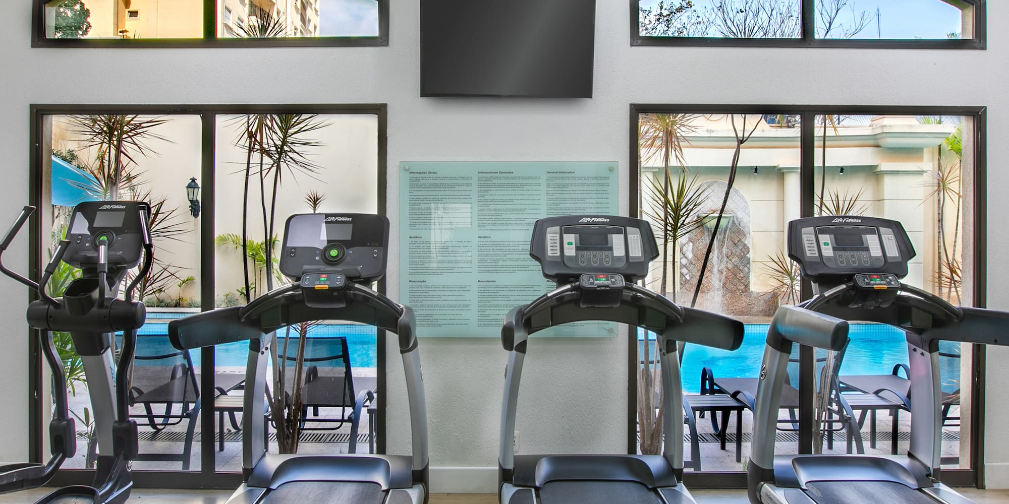 a room with treadmills and a pool in the background