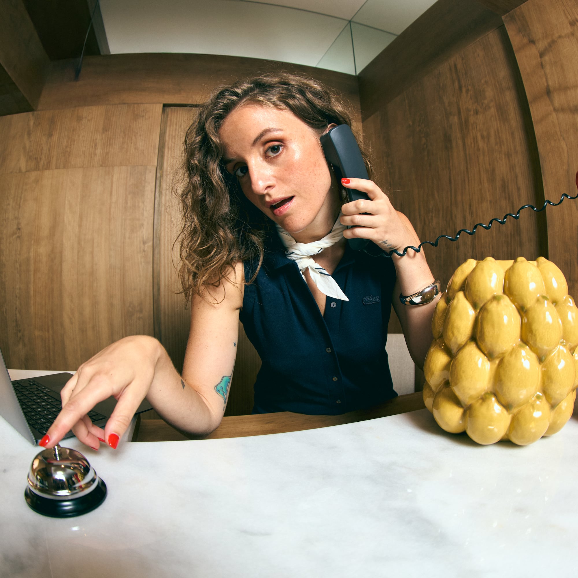a woman sitting at a desk with a laptop and phone