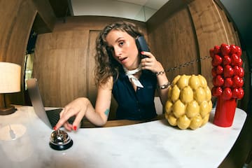 a woman sitting at a desk with a laptop and phone