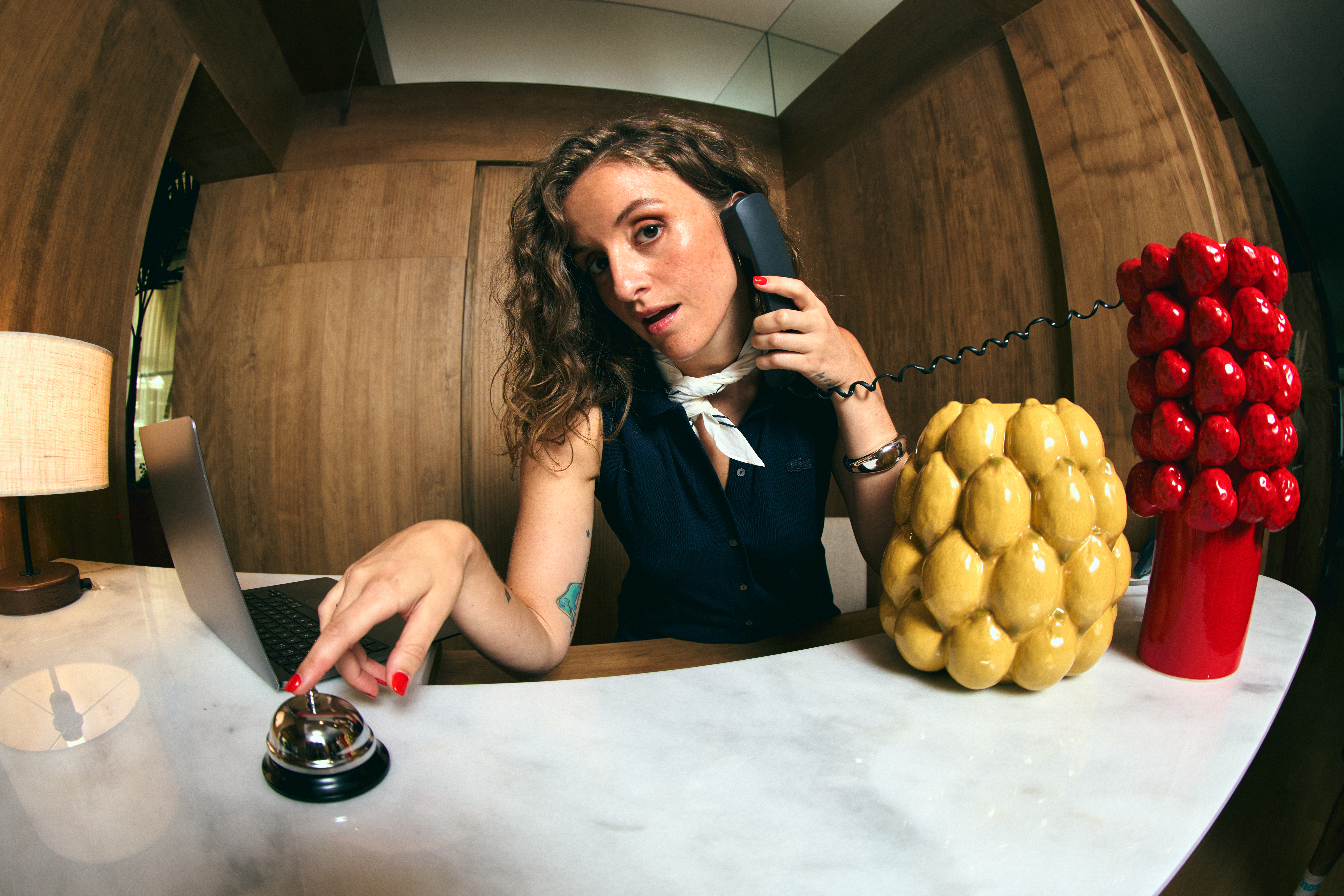 a woman sitting at a desk with a laptop and phone