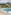 Tropical beach with people swimming, hillside village, palm trees, and blue ocean.