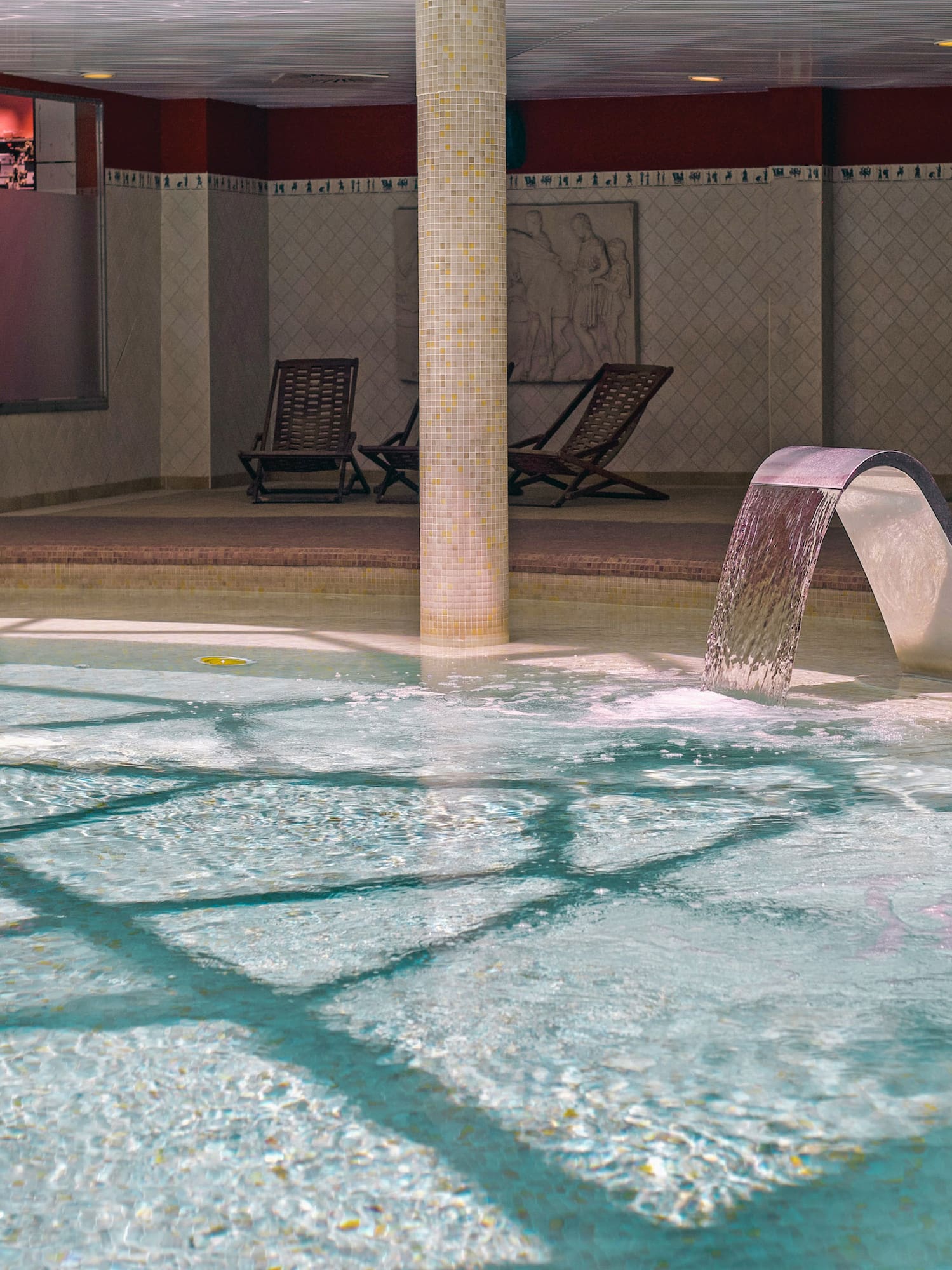 Indoor hydrotherapy pool with active water features and spa loungers.