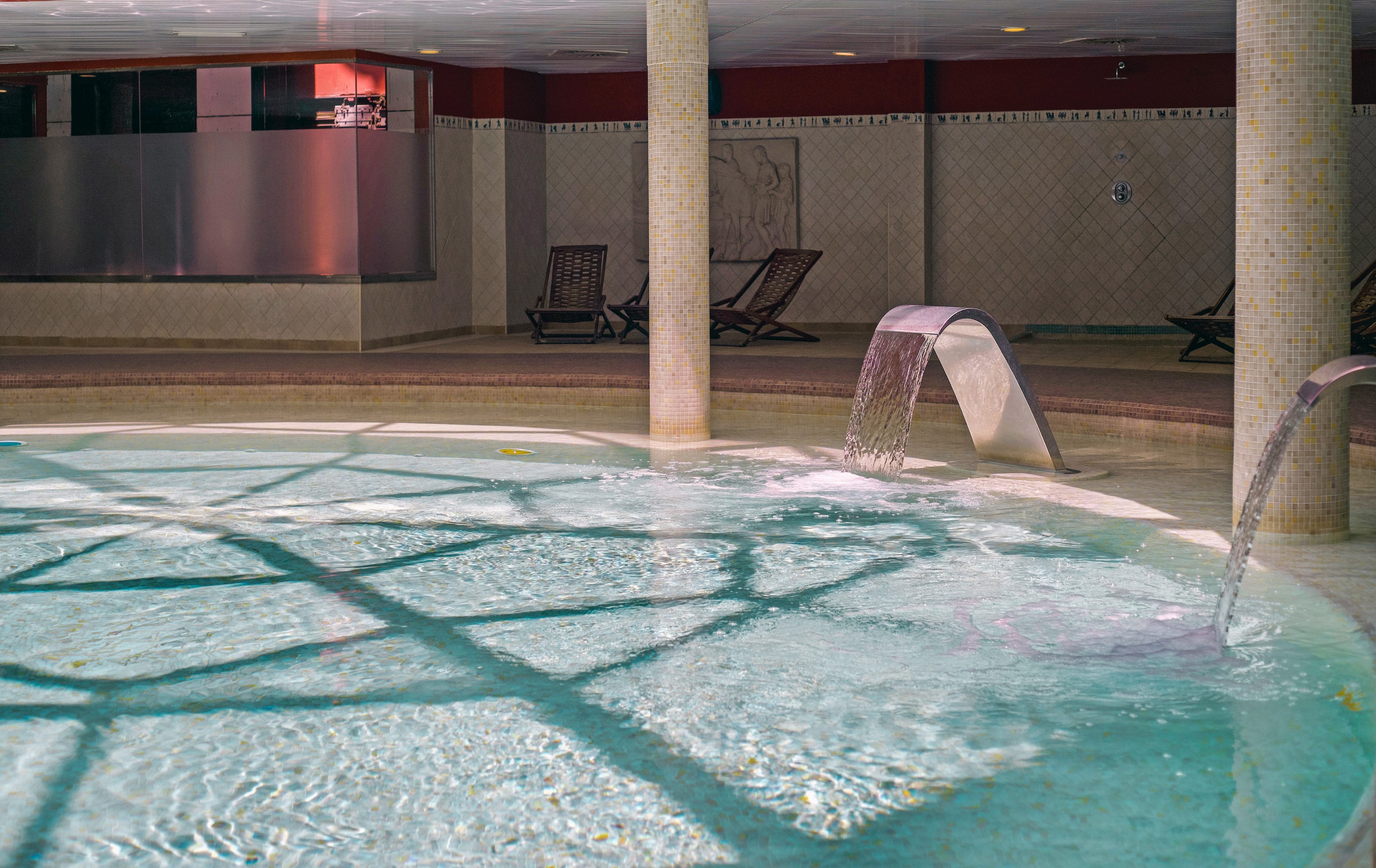 Indoor hydrotherapy pool with active water features and spa loungers.