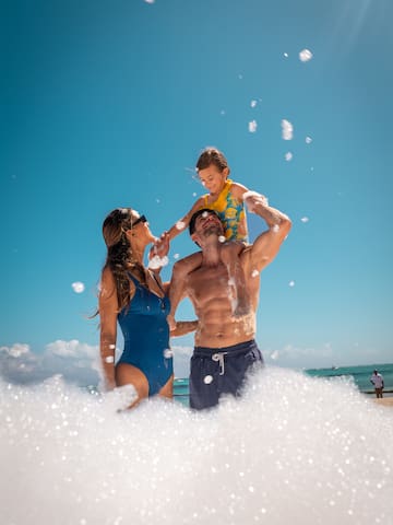 a man and woman with a child on his shoulders on a beach