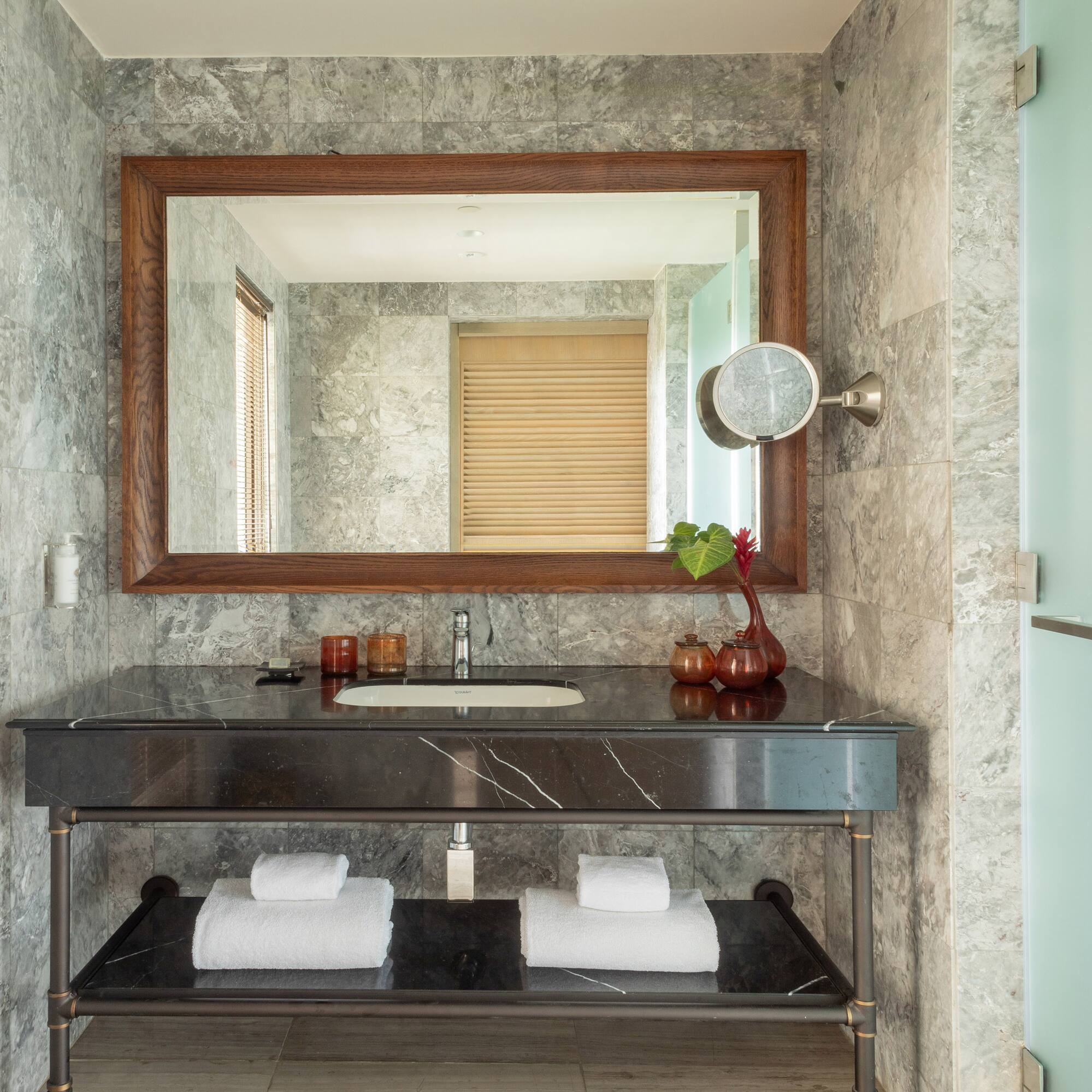 Modern bathroom vanity with gray marble walls, black countertop, and large mirror.