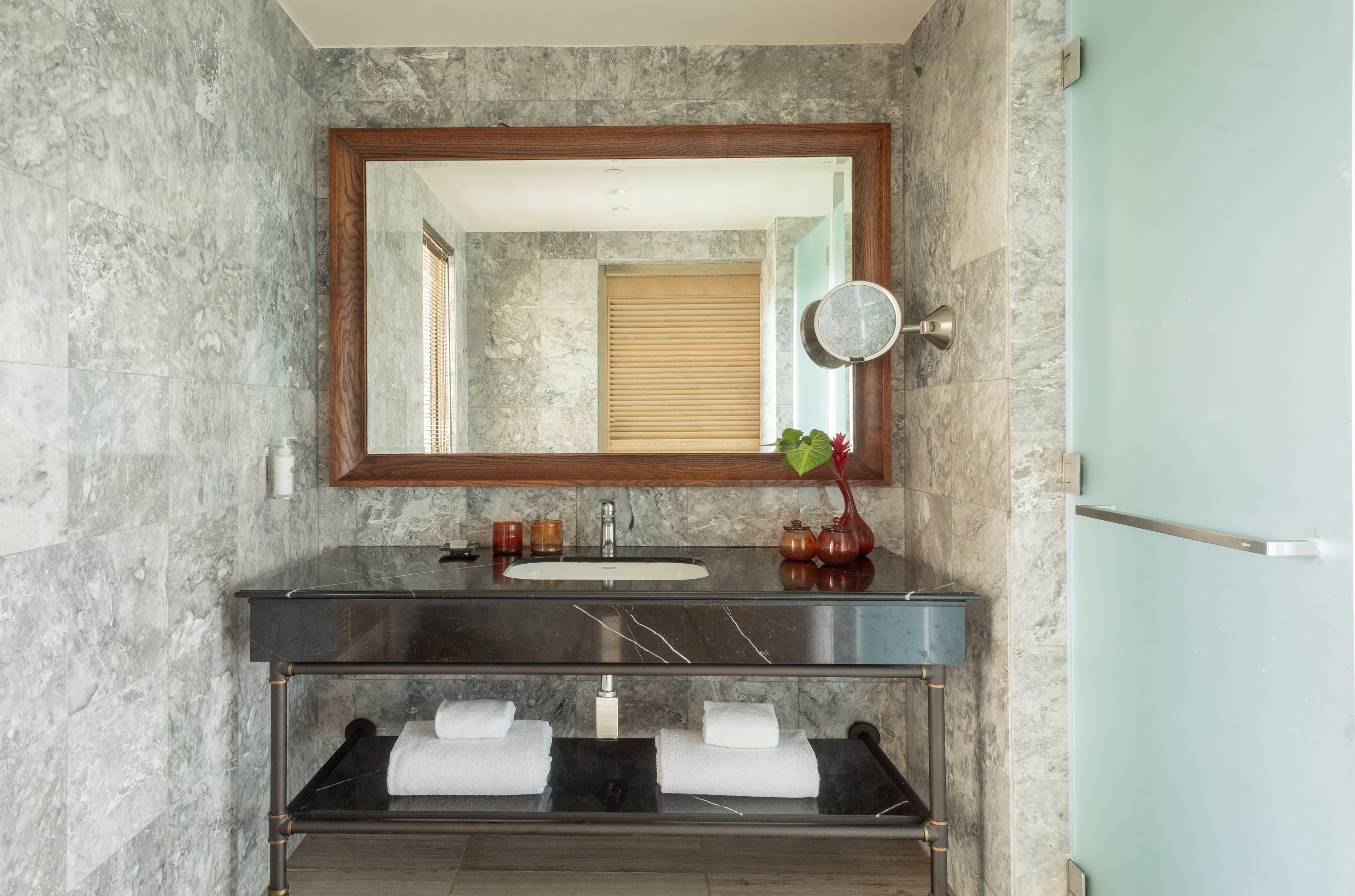 Modern bathroom vanity with gray marble walls, black countertop, and large mirror.