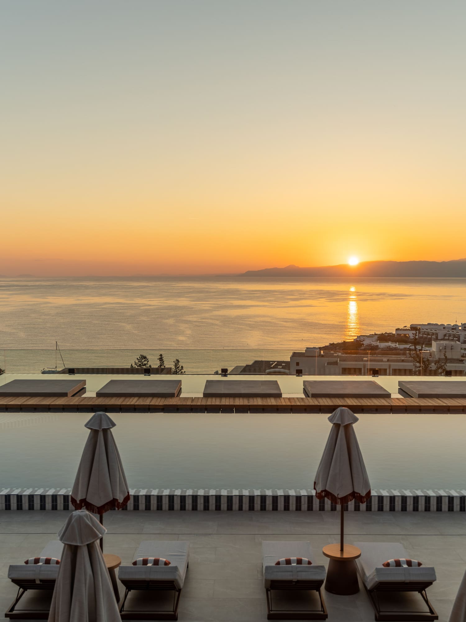 Luxury resort infinity pool at sunset overlooking ocean and distant island.