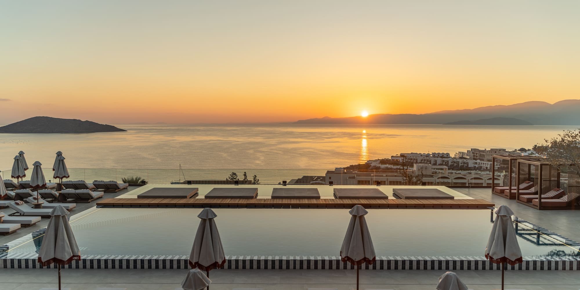 a pool with umbrellas and chairs overlooking a body of water