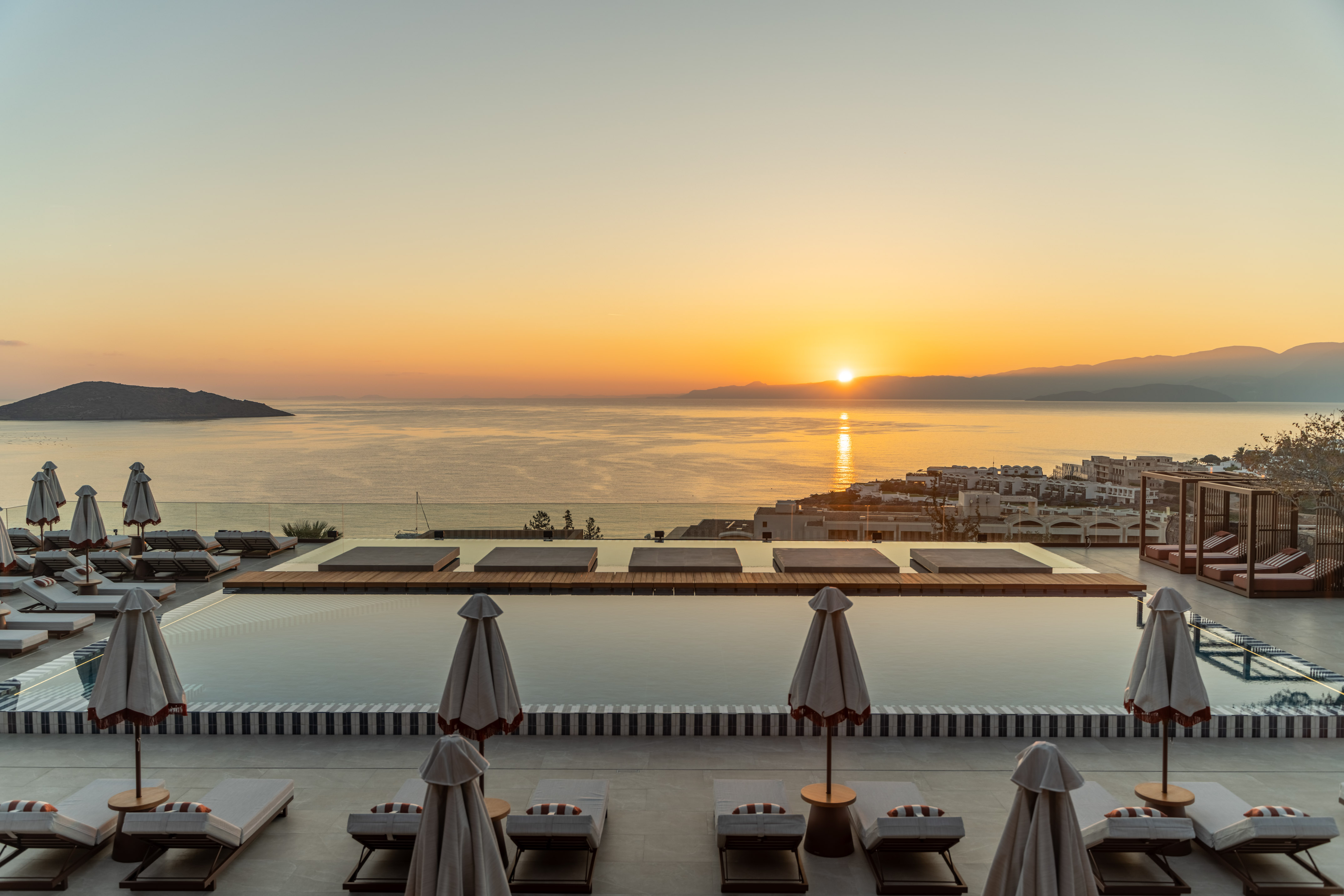 Luxury resort infinity pool at sunset overlooking ocean and distant island.