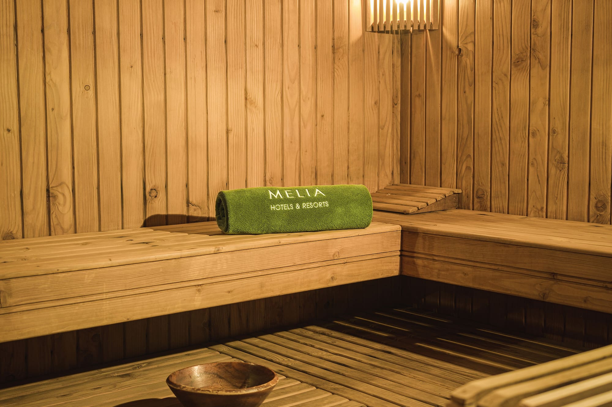 a wooden sauna with a bowl and a towel