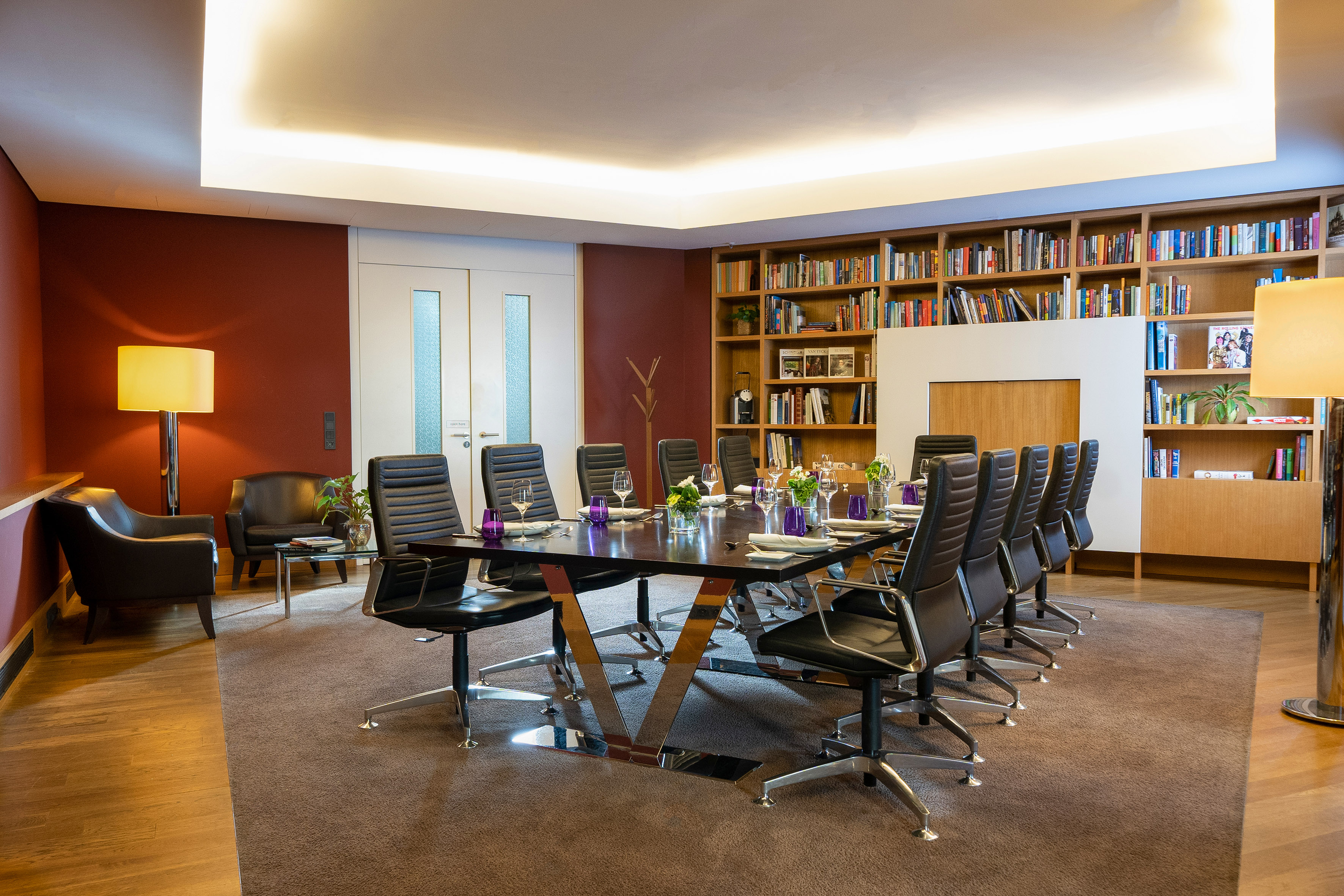 Professional meeting room with long table, leather chairs, and extensive library.