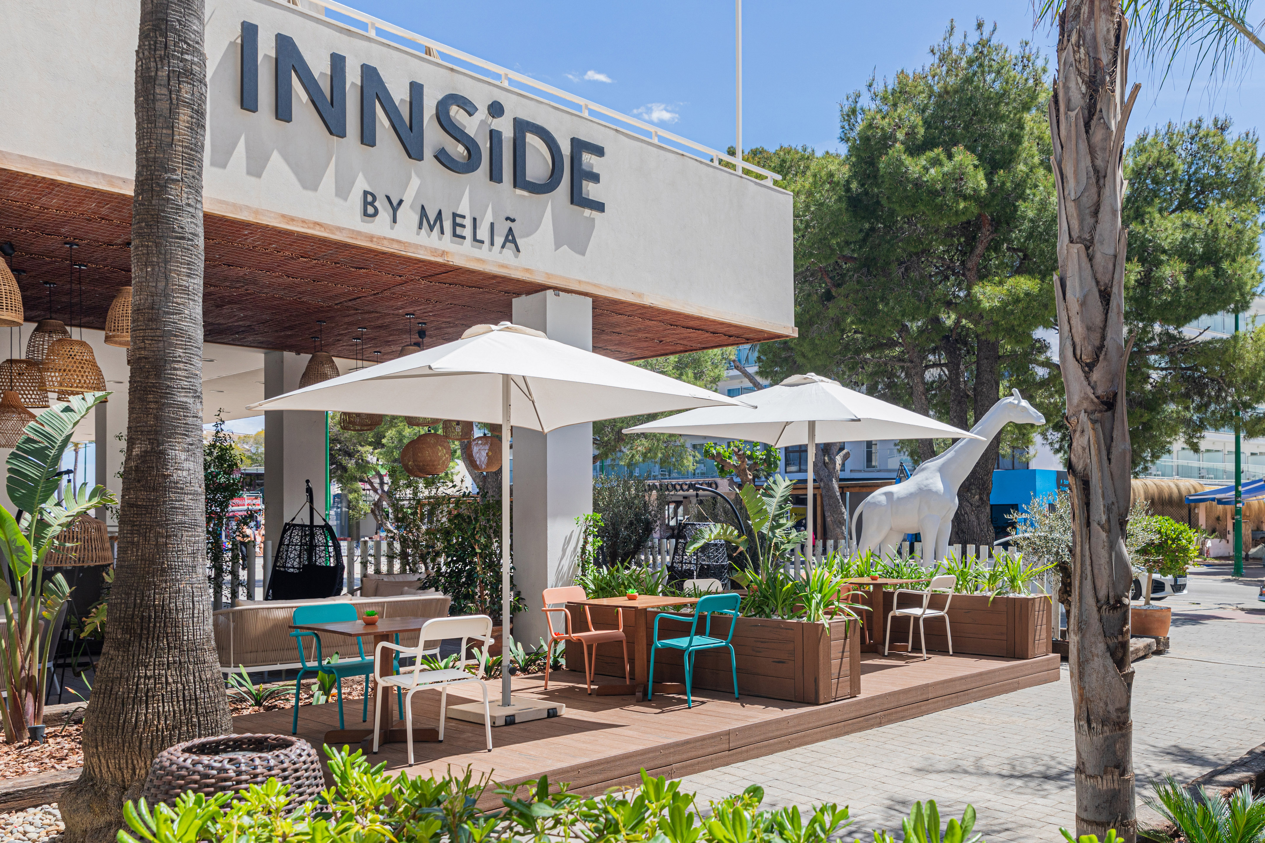 INNSiDE BY MELIA hotel terrace with colorful seating, umbrellas, and white giraffe.