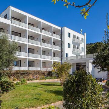 a white building with balconies and trees