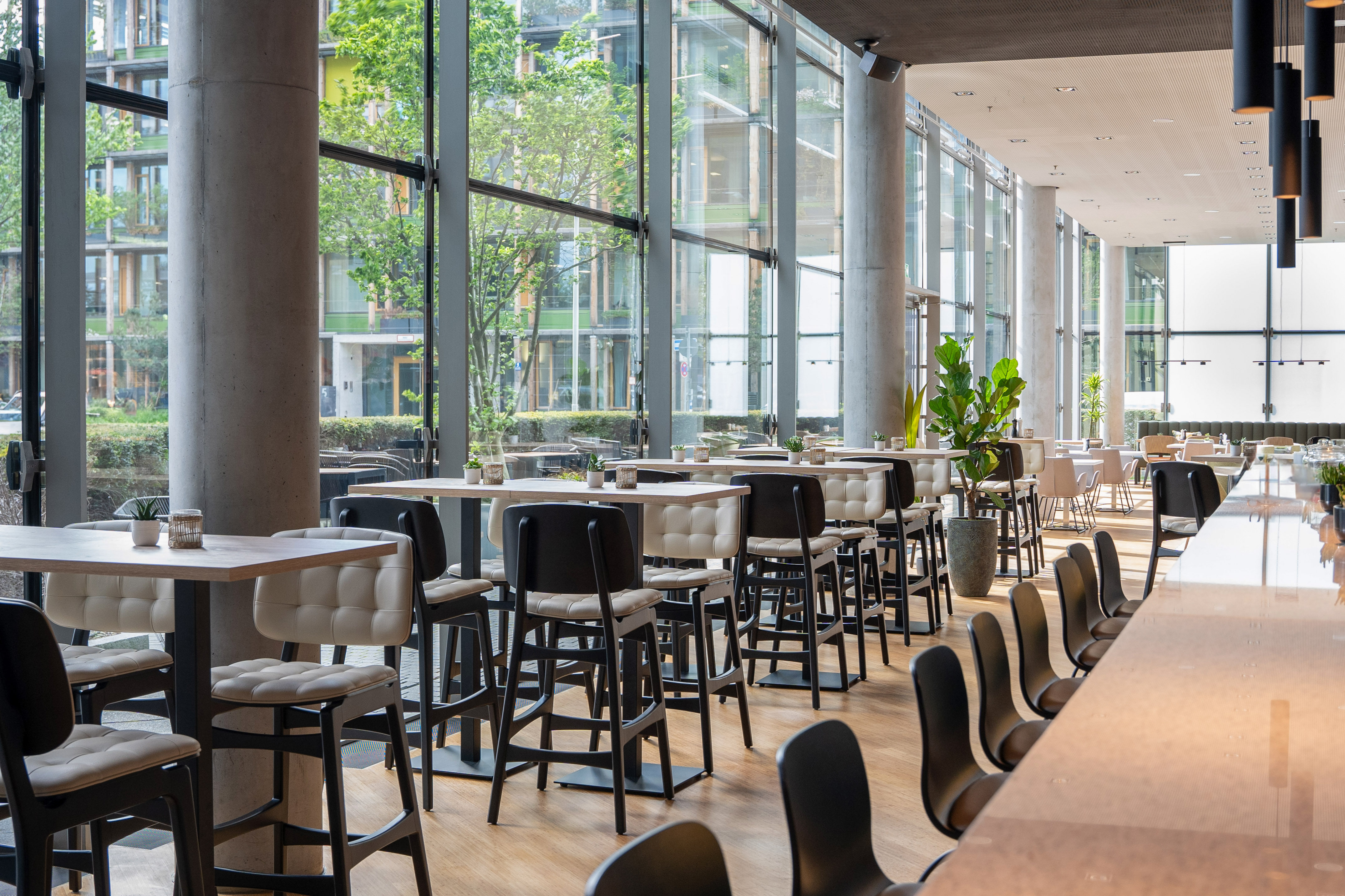 Modern cafe with upholstered bar stools, high tables, and large windows.