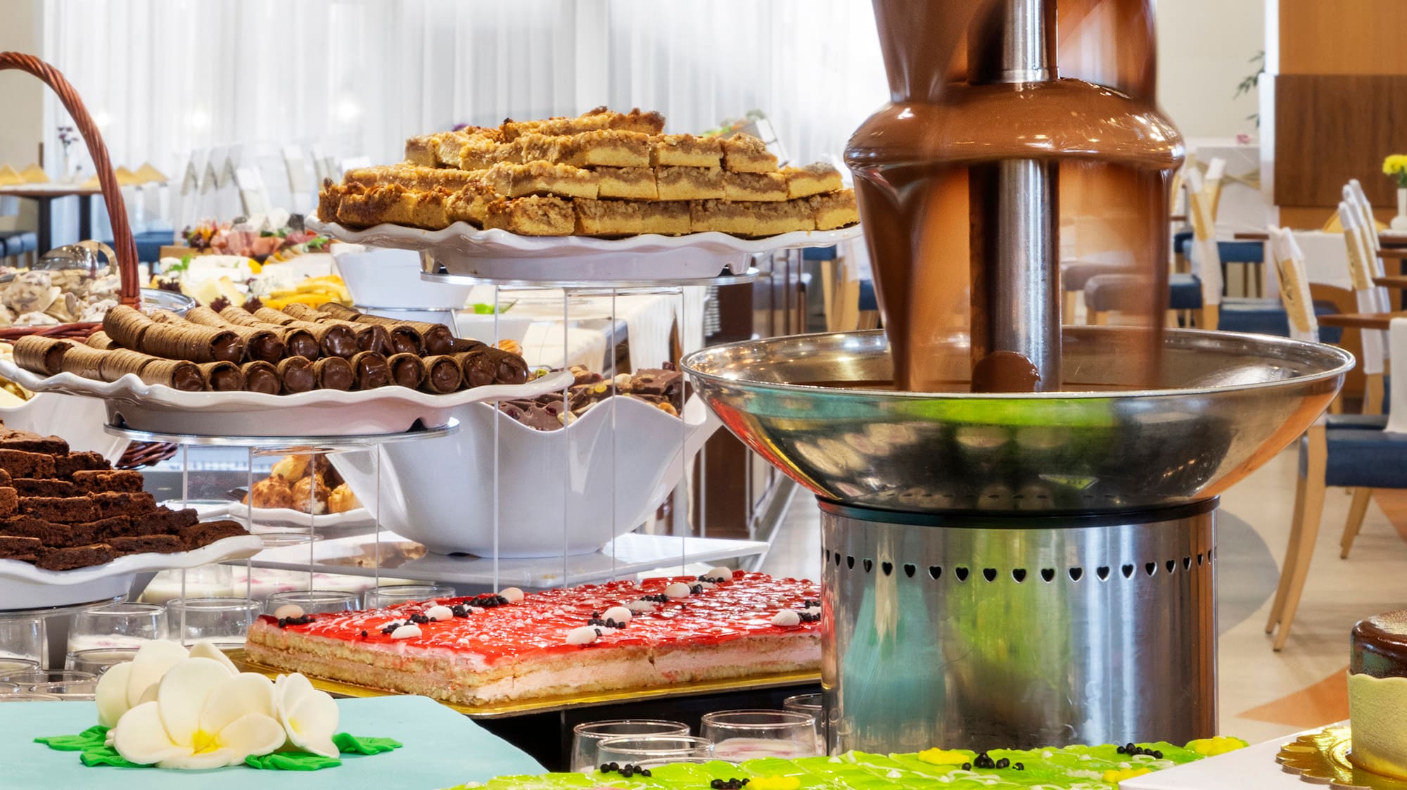 a chocolate fountain on a table with many different cakes