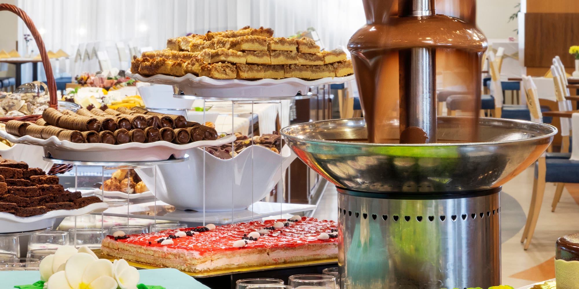 a chocolate fountain on a table with many different cakes