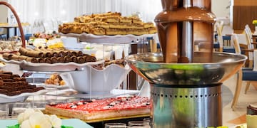 a chocolate fountain on a table with many different cakes