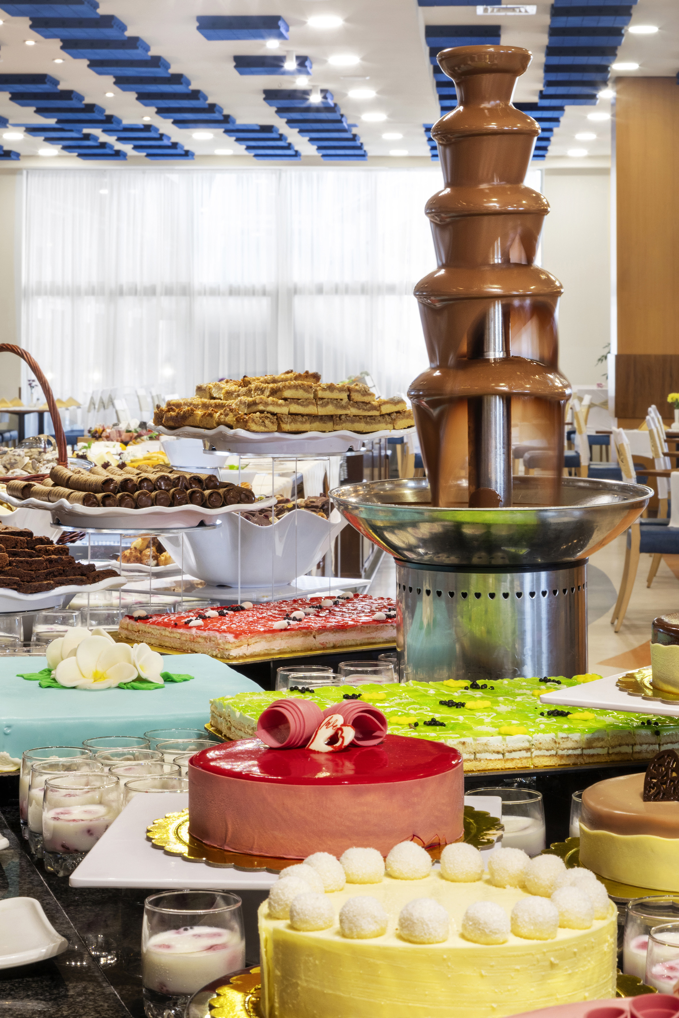 a chocolate fountain on a table with many different cakes