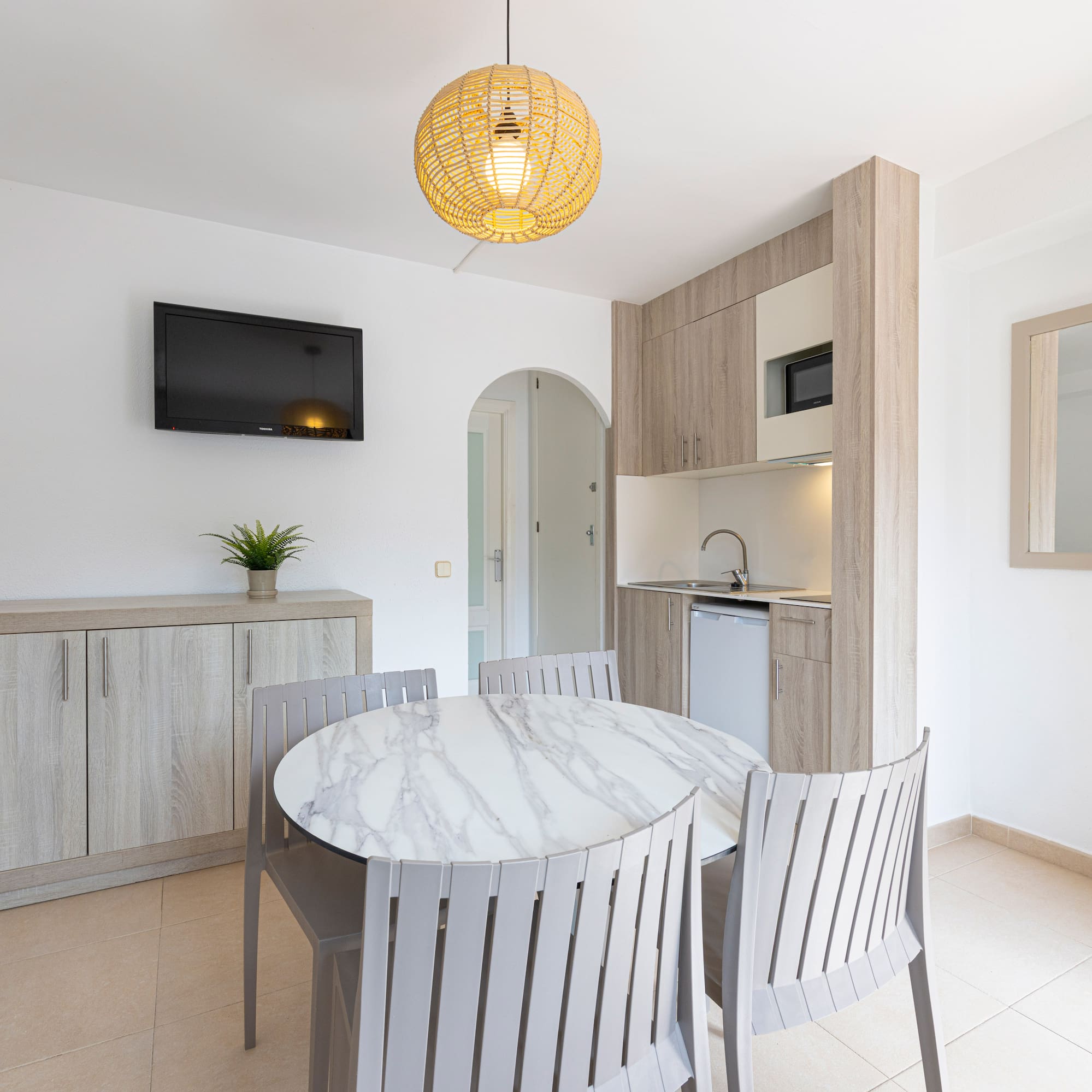 Bright studio apartment with modern kitchenette, round dining table, and TV.