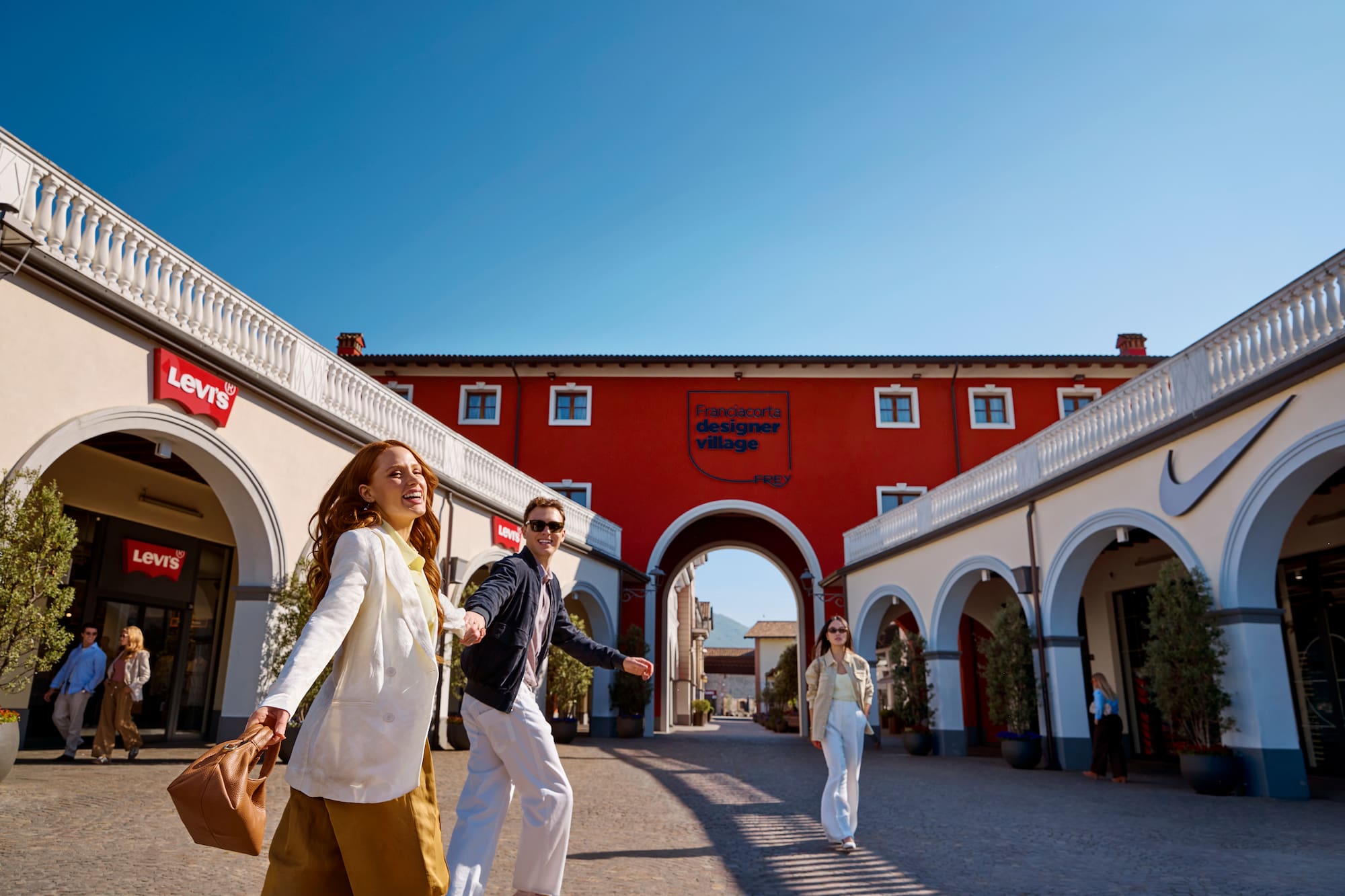 Shoppers walking past Levi's, Nike at Franciacorta Designer Village outlet.