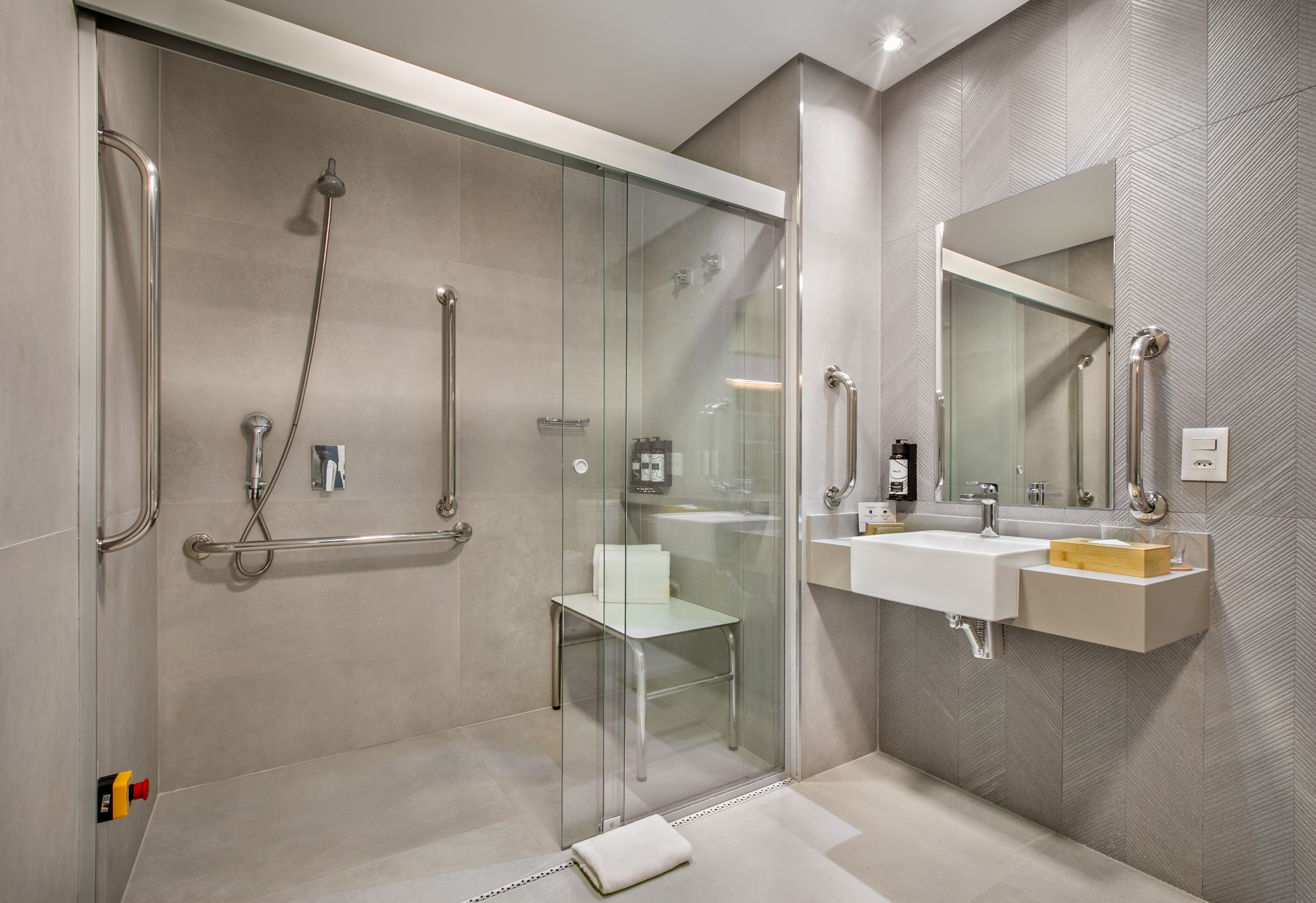 Modern accessible bathroom with roll-in shower, grab bars, and shower seat.