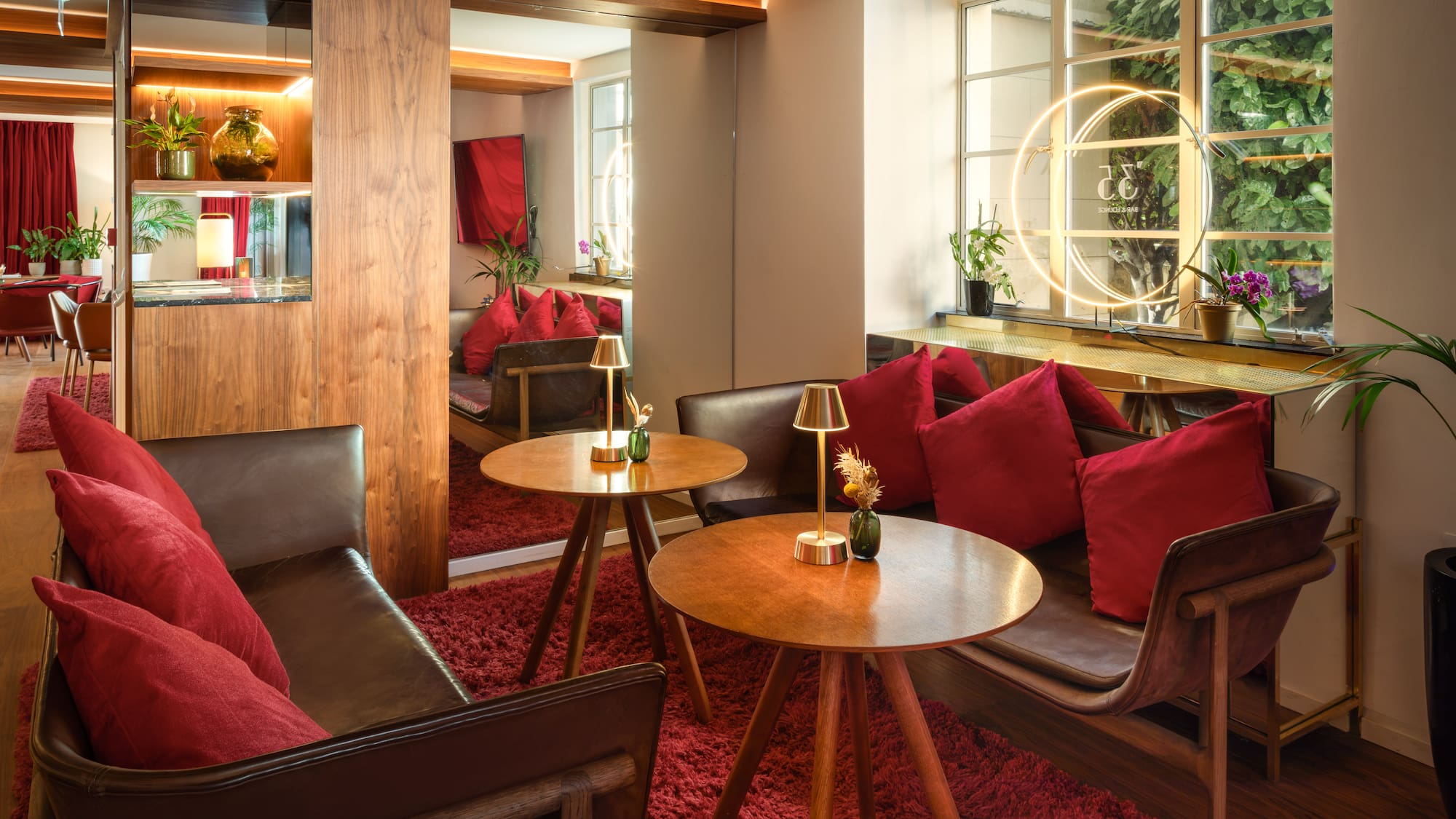Cozy hotel lounge with red carpet, leather seating, wood tables, warm lighting.