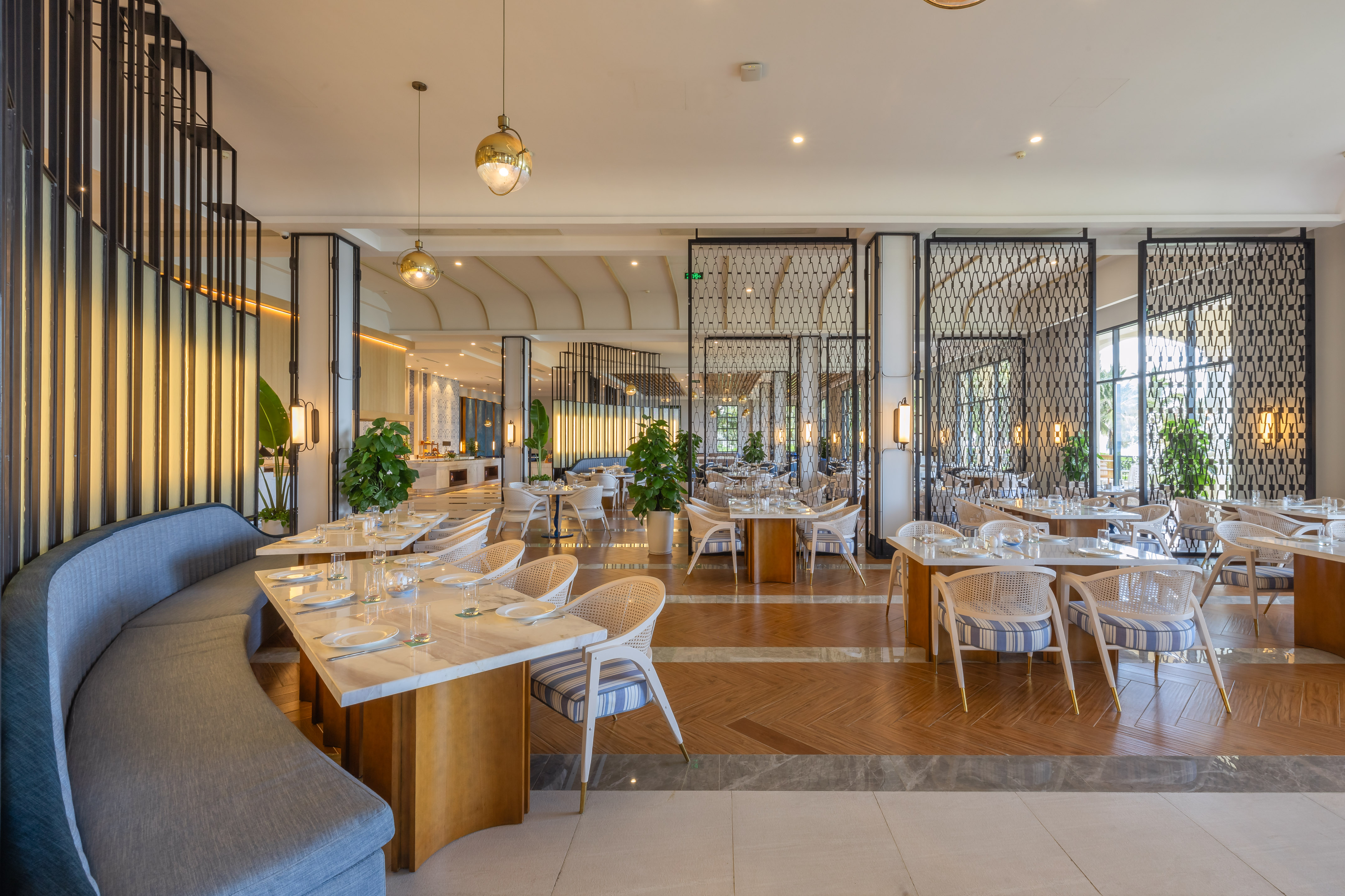 Elegant hotel restaurant with marble tables, blue seating, and decorative screens.