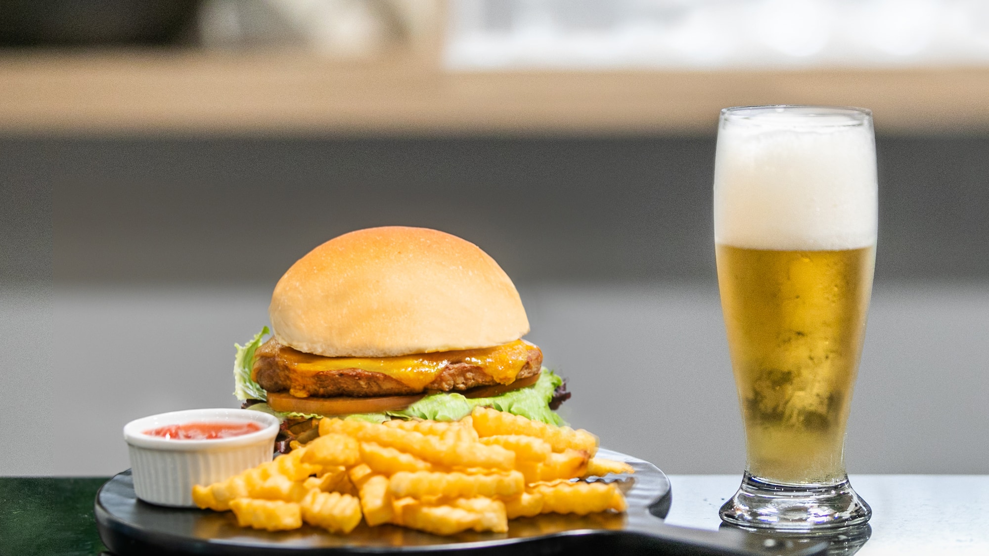 a burger and fries on a plate next to a glass of beer