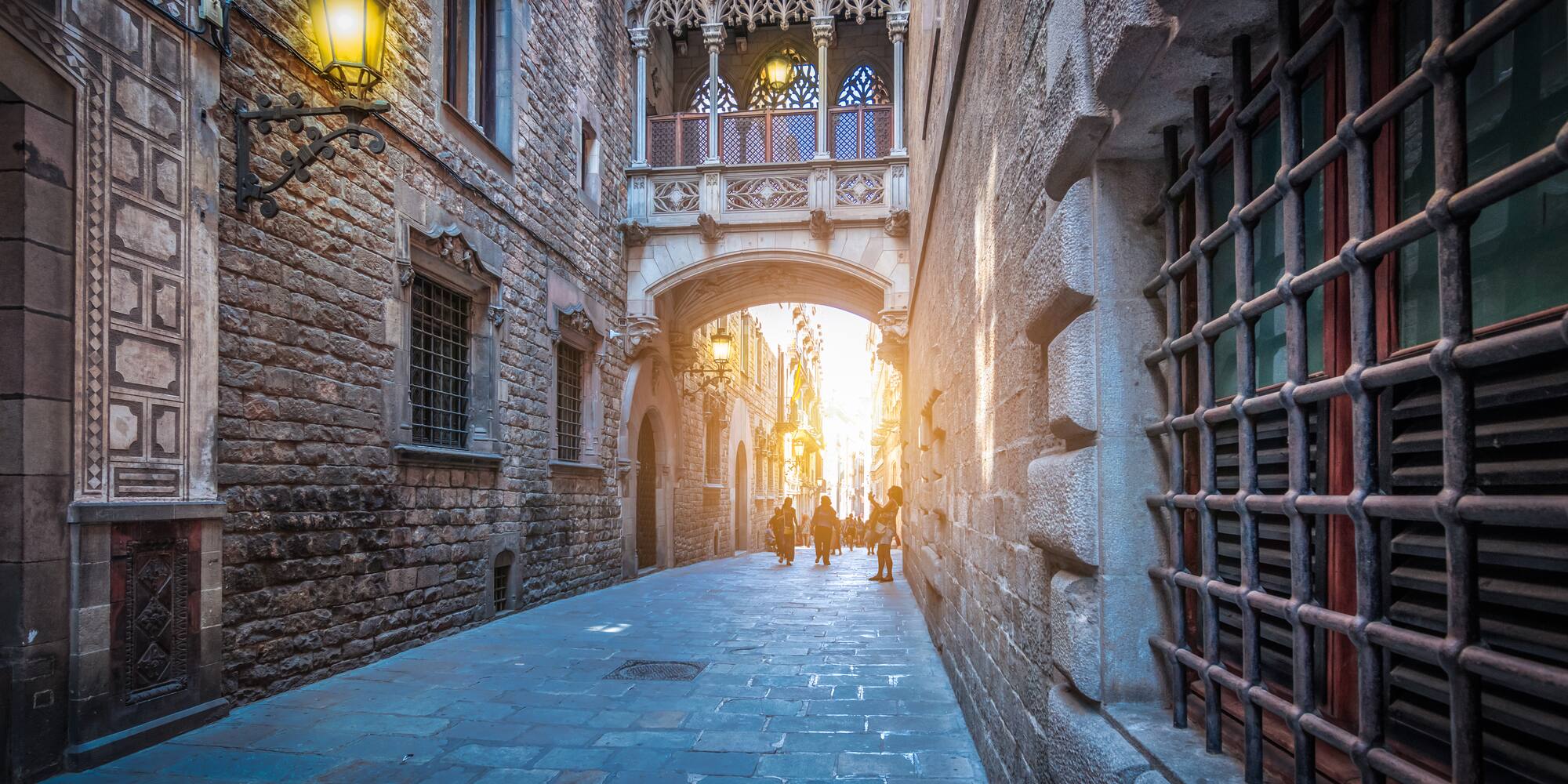 Pont del Bisbe en el Barrio Gótico de Barcelona, calle gótica con luz solar.