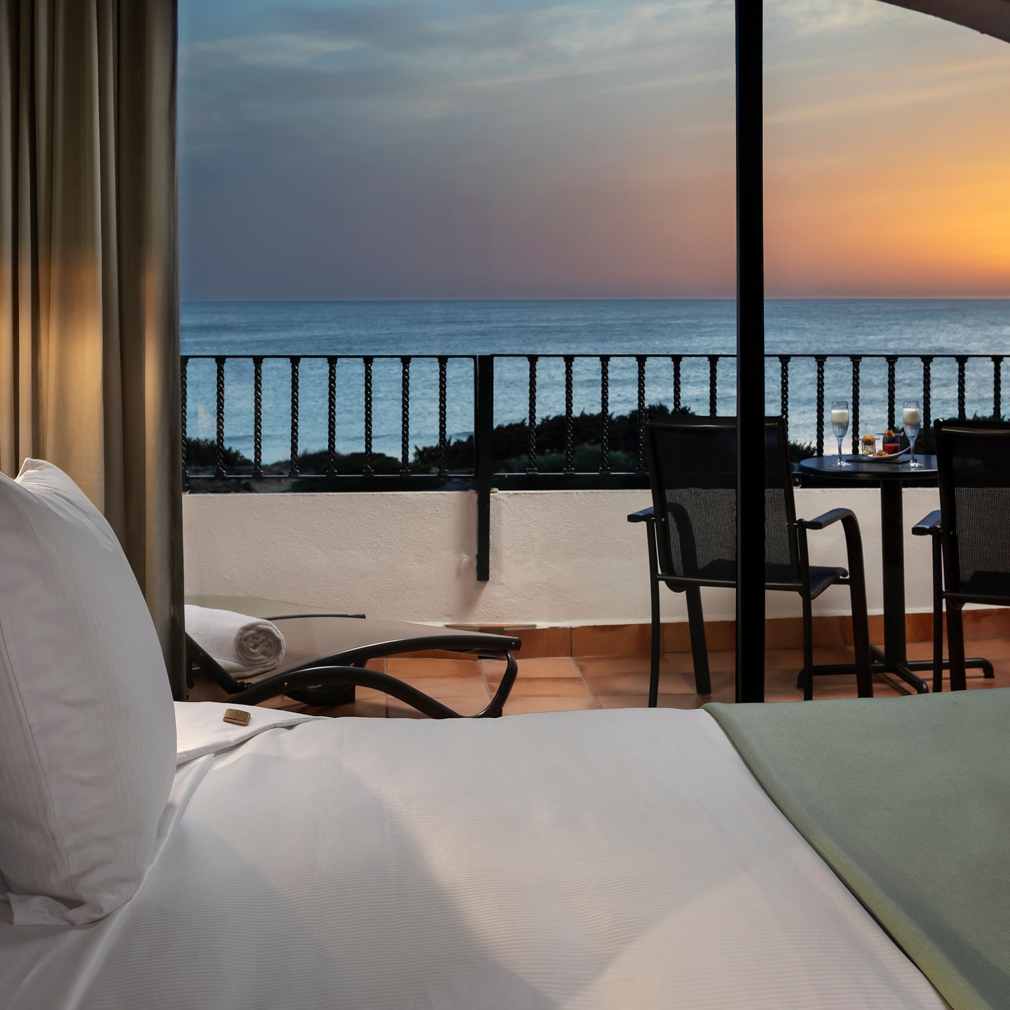 a room with a view of the ocean and a table and chairs