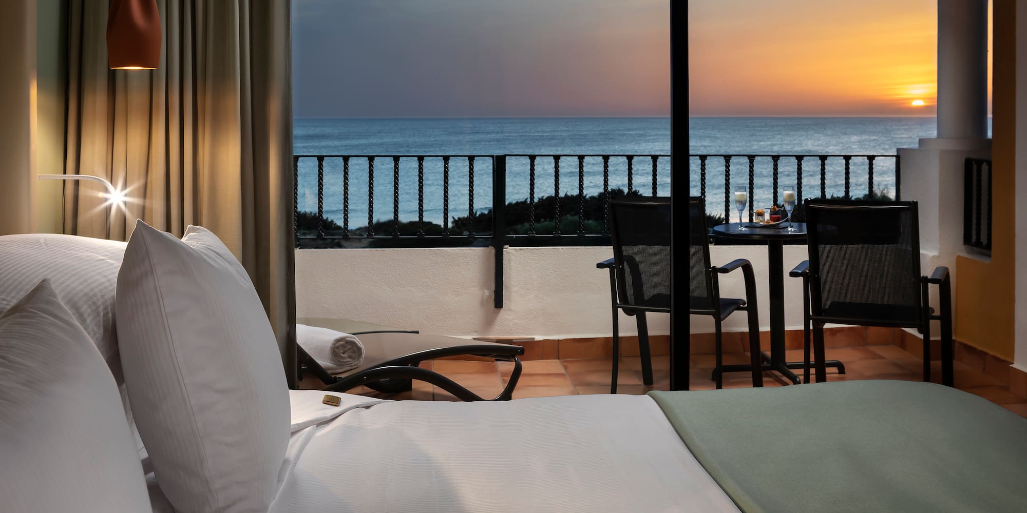 a room with a view of the ocean and a table and chairs