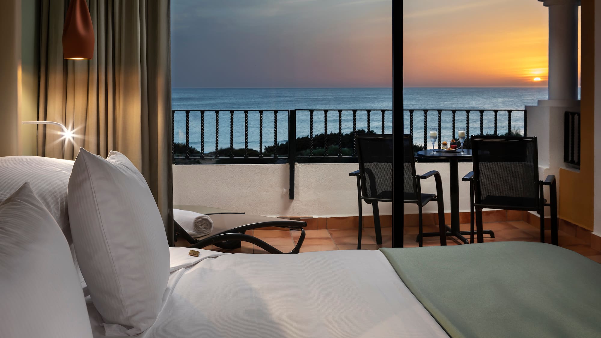 a room with a view of the ocean and a table and chairs