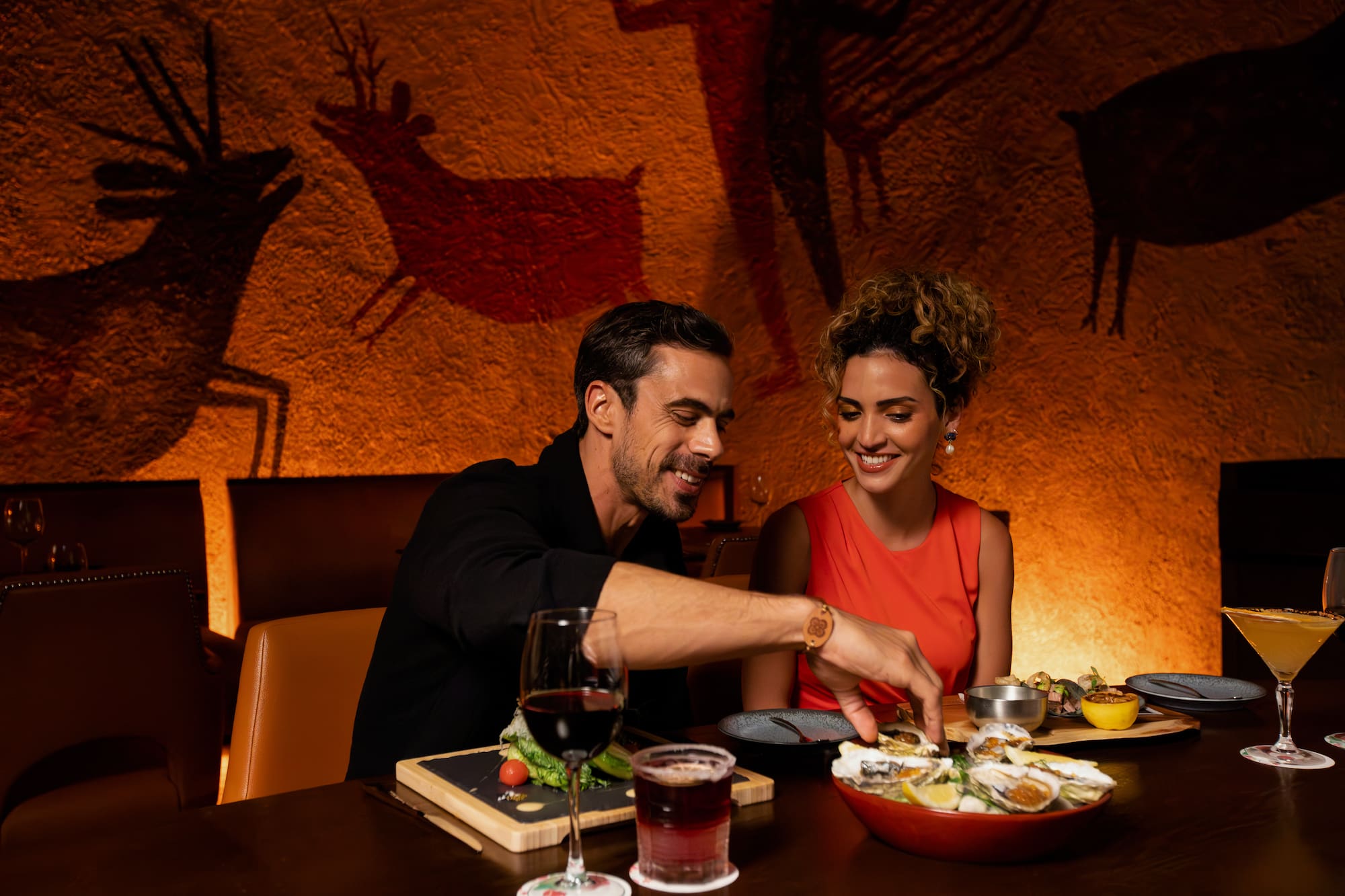 a man and woman sitting at a table with food