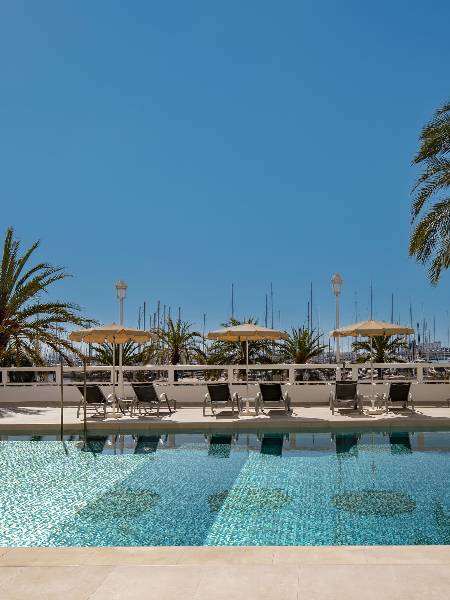 a pool with chairs and umbrellas by a building