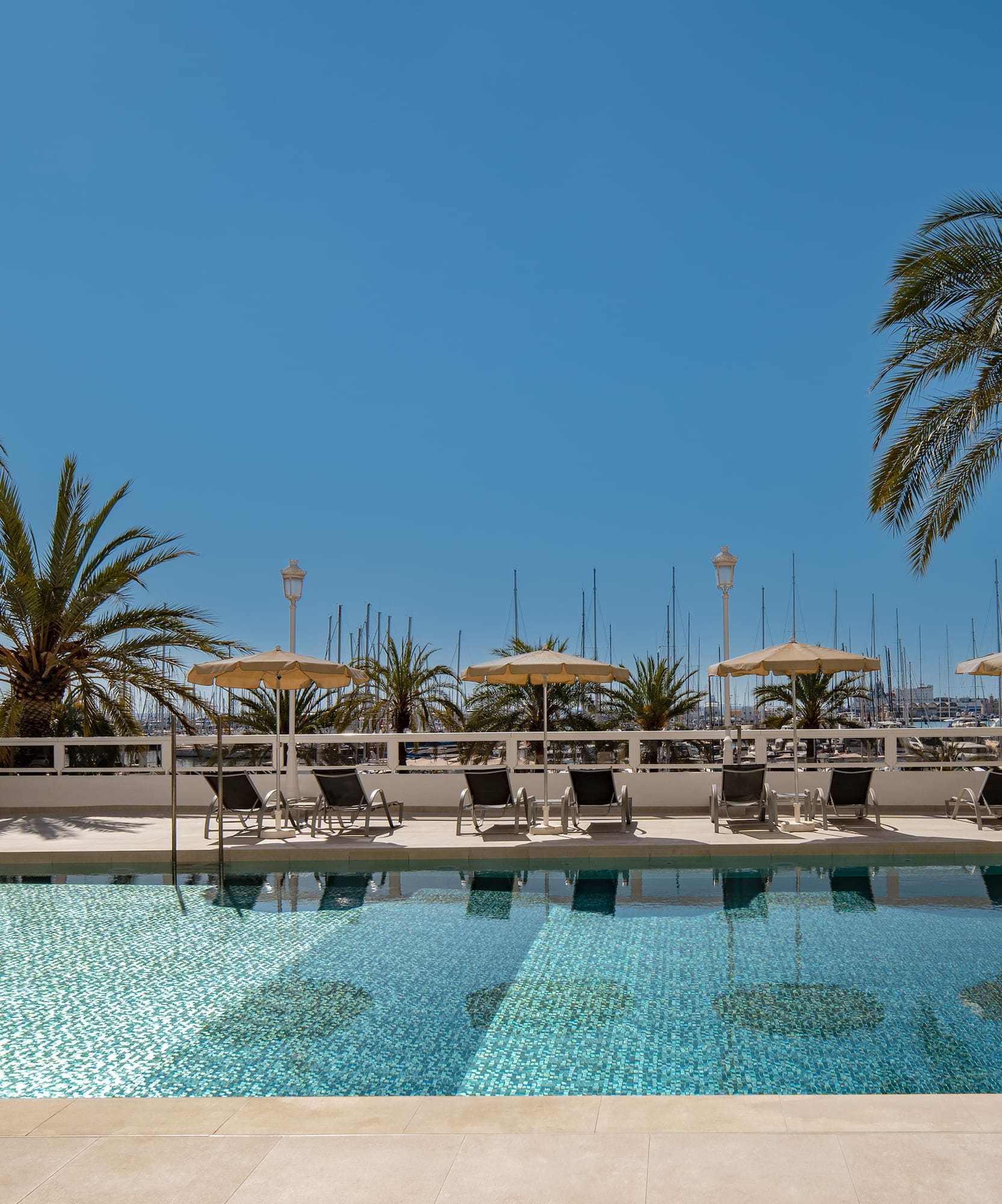 a pool with chairs and umbrellas by a building