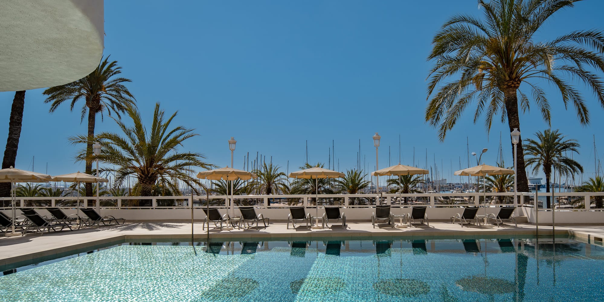 a pool with chairs and umbrellas by a building