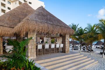 a bar with chairs and a thatched roof on a beach