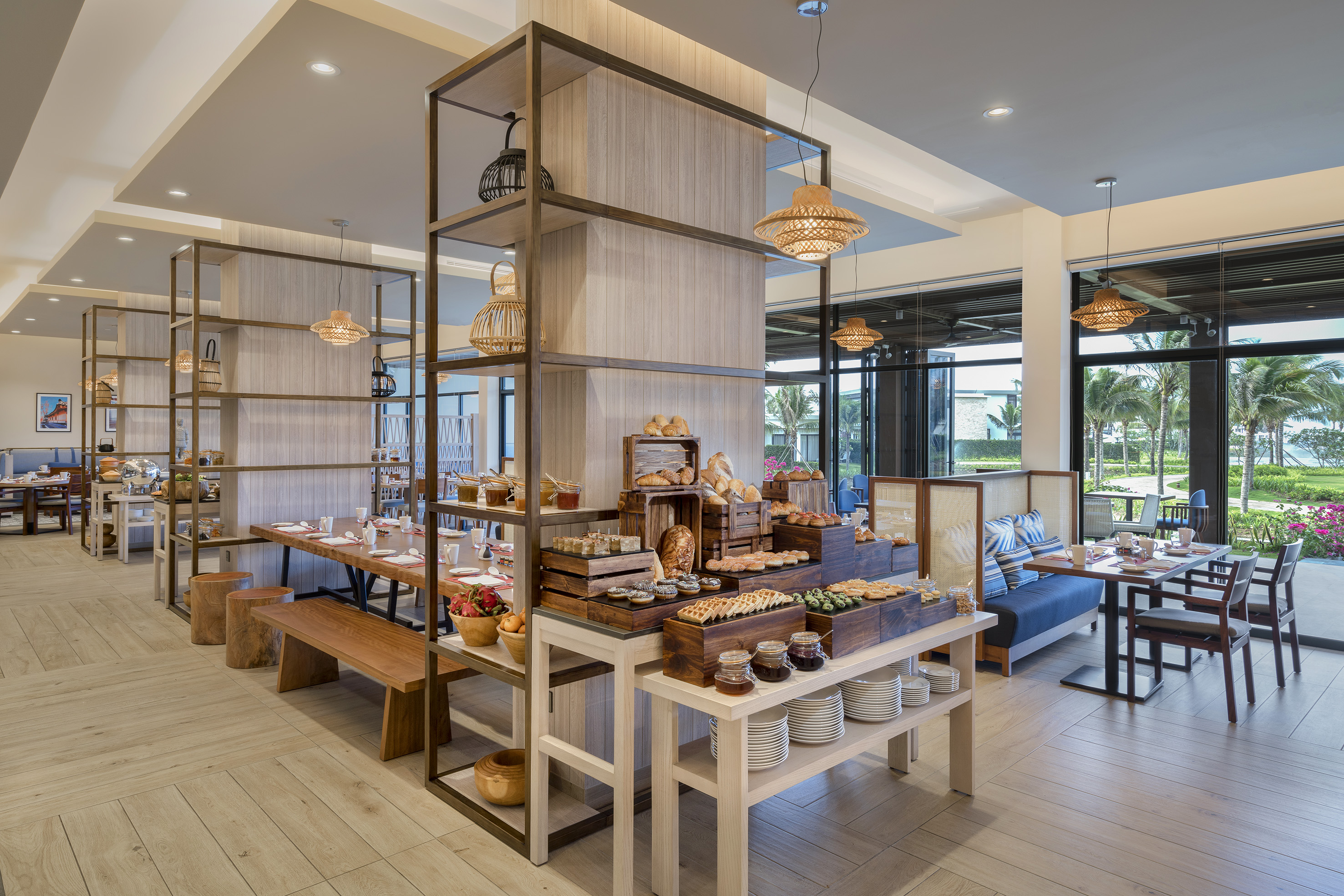Bright hotel buffet restaurant with varied breakfast spread, ocean view.