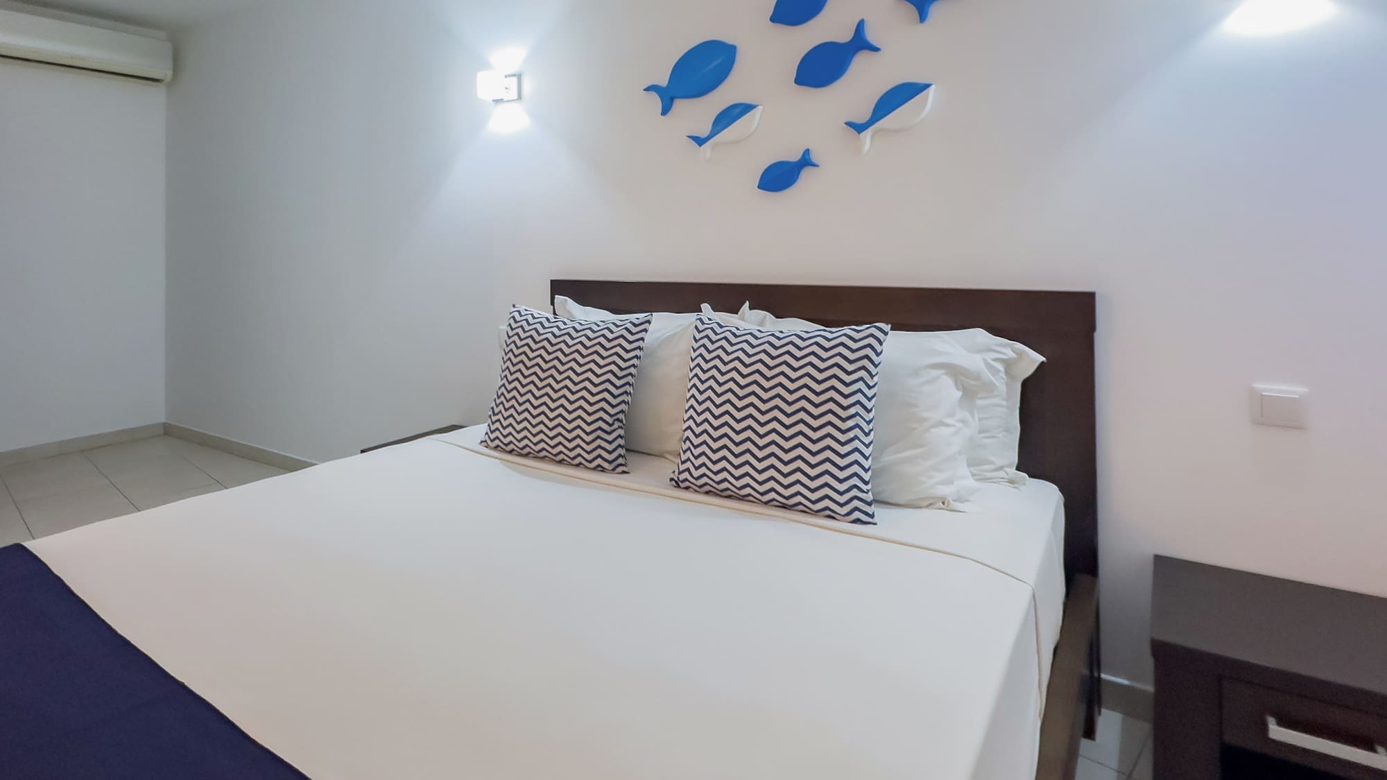 a bed with pillows and a fish on the wall