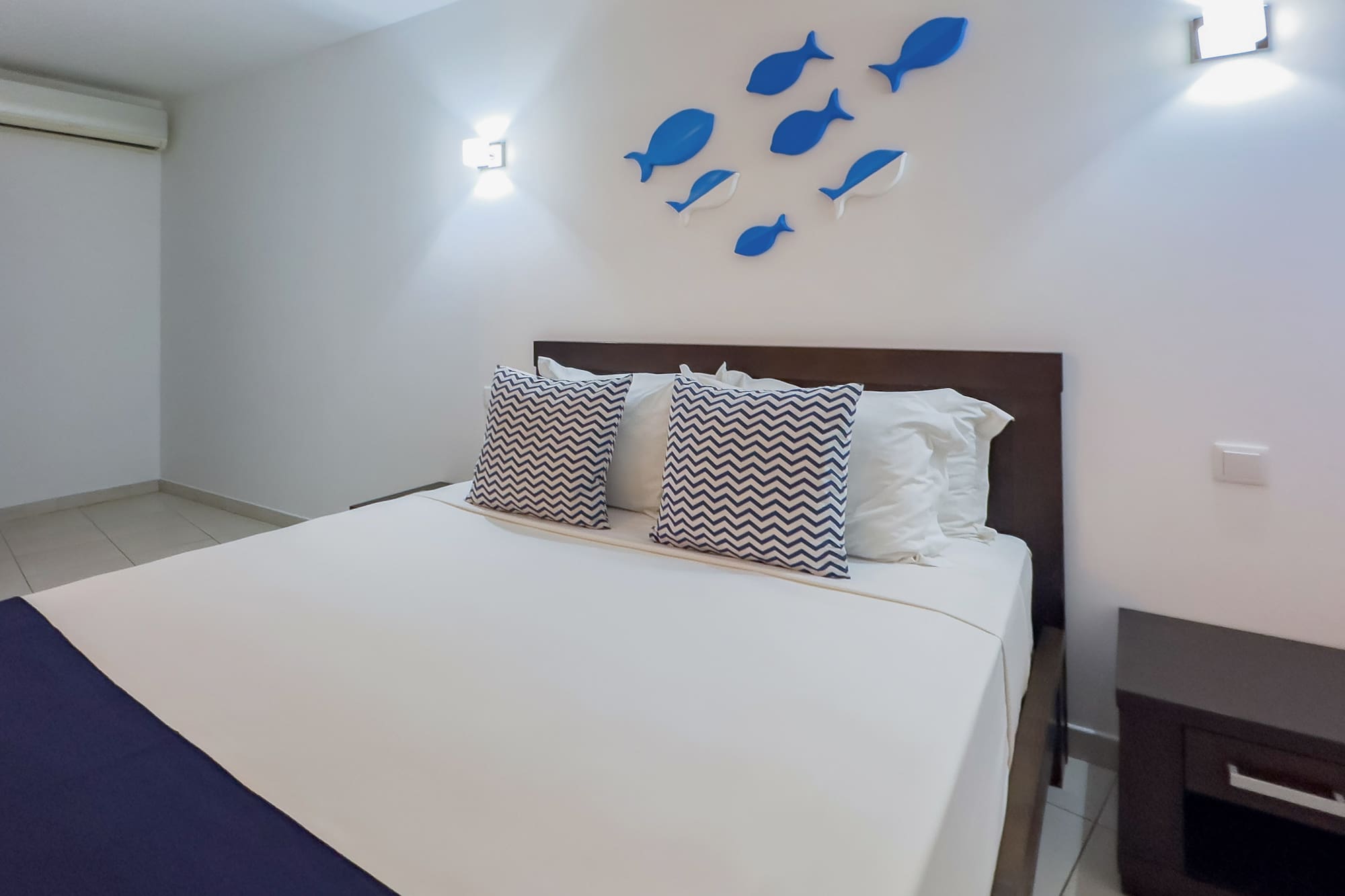 a bed with pillows and a fish on the wall