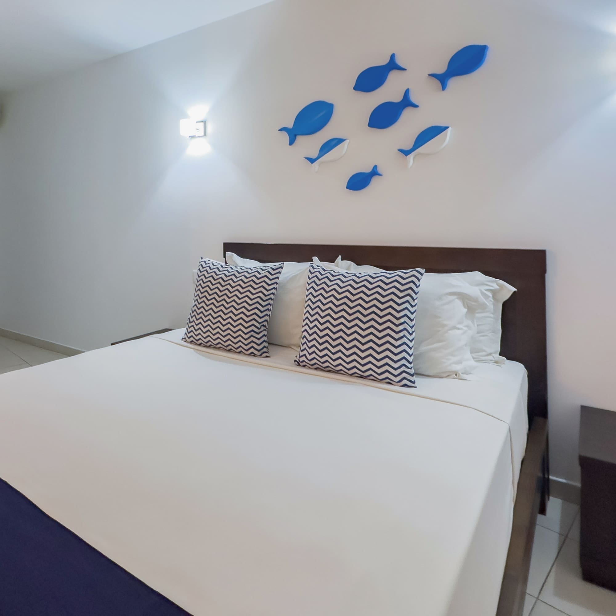 a bed with pillows and a fish on the wall