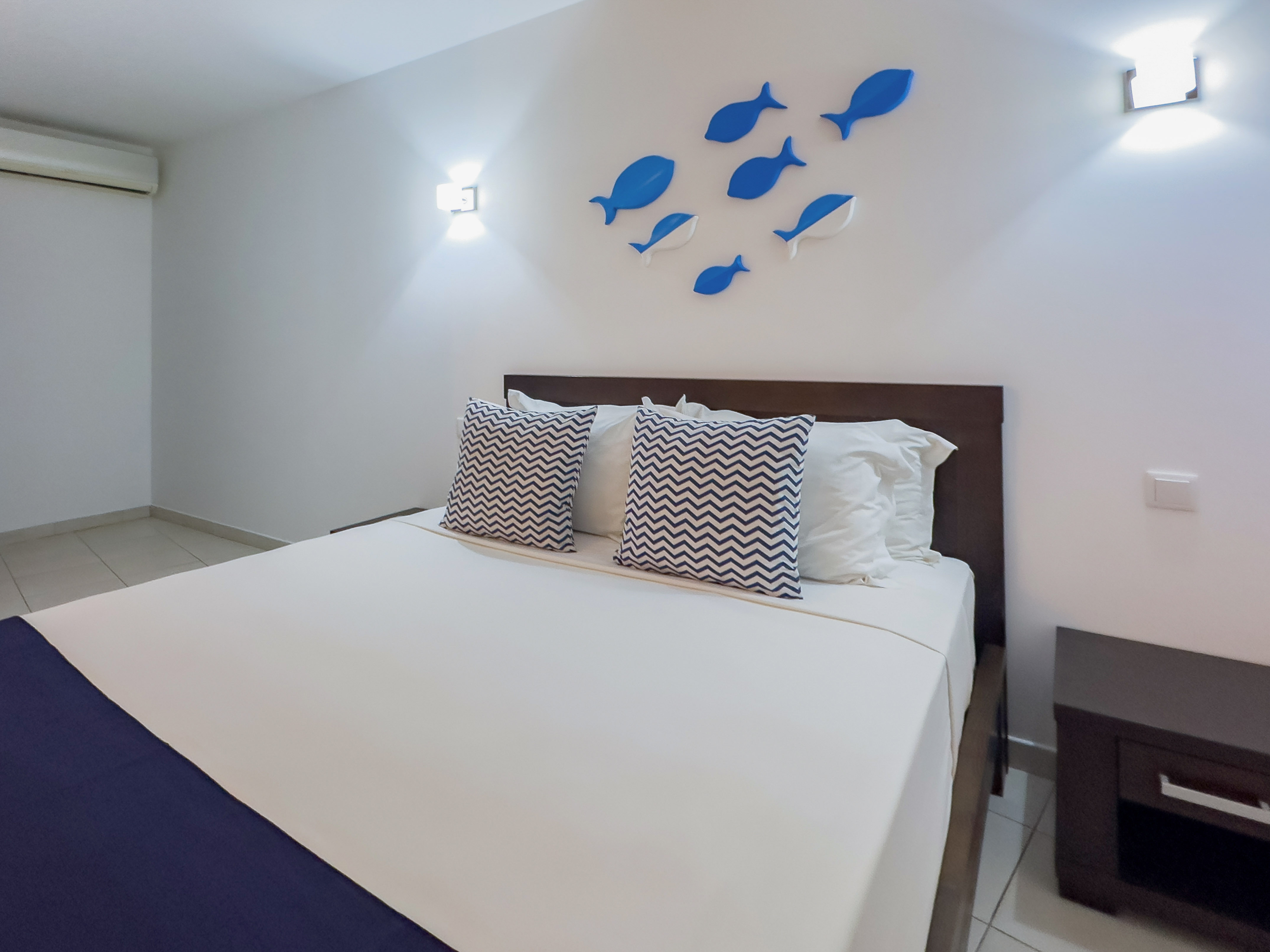 a bed with pillows and a fish on the wall