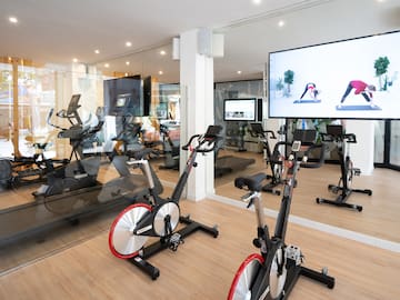 a room with exercise bikes and a large screen