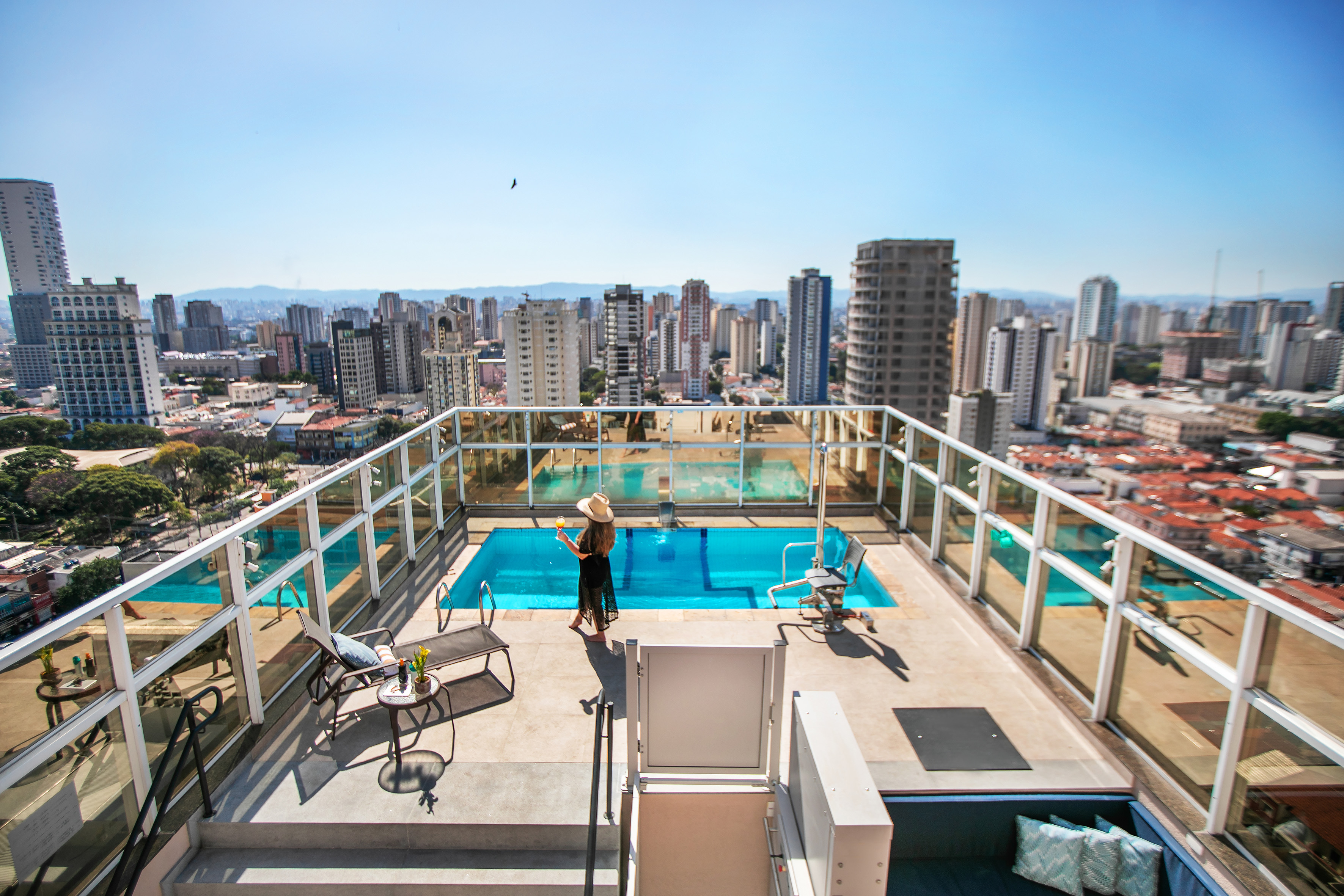 a woman standing on a rooftop with a pool and a city in the background