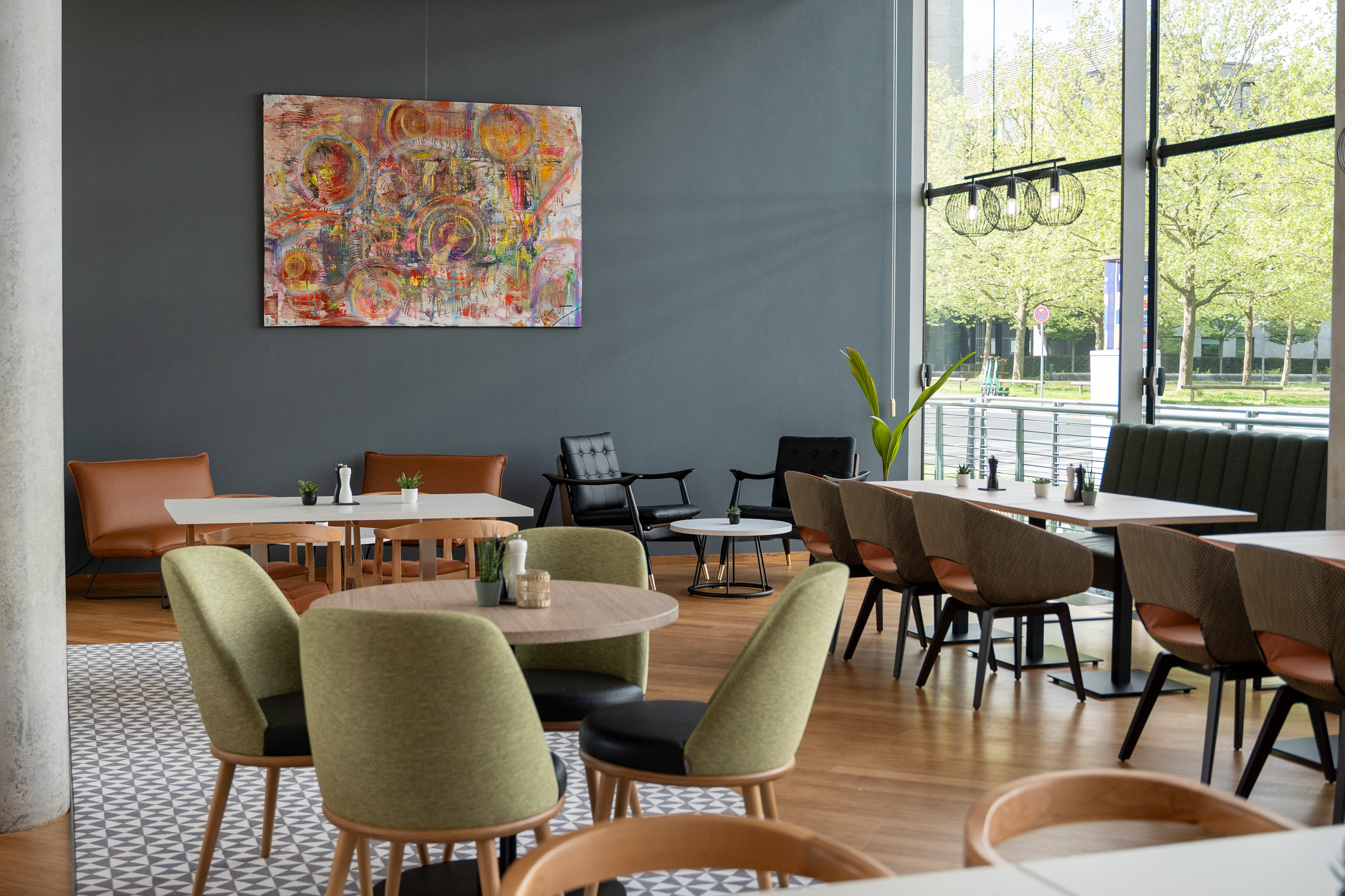 Modern restaurant interior with diverse seating, abstract art, large bright windows.