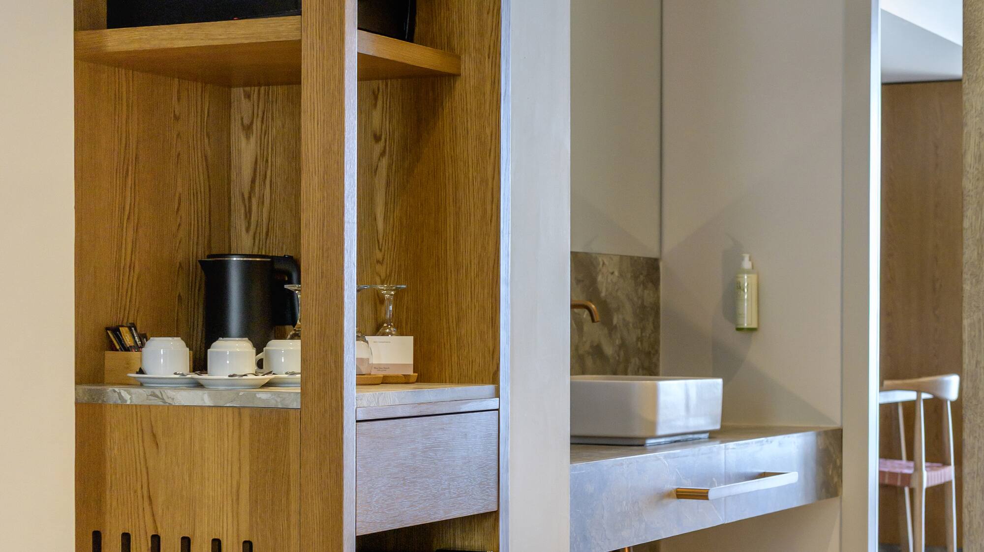 Hotel room: wooden cabinet, mini-fridge, coffee station, and bathroom vanity.